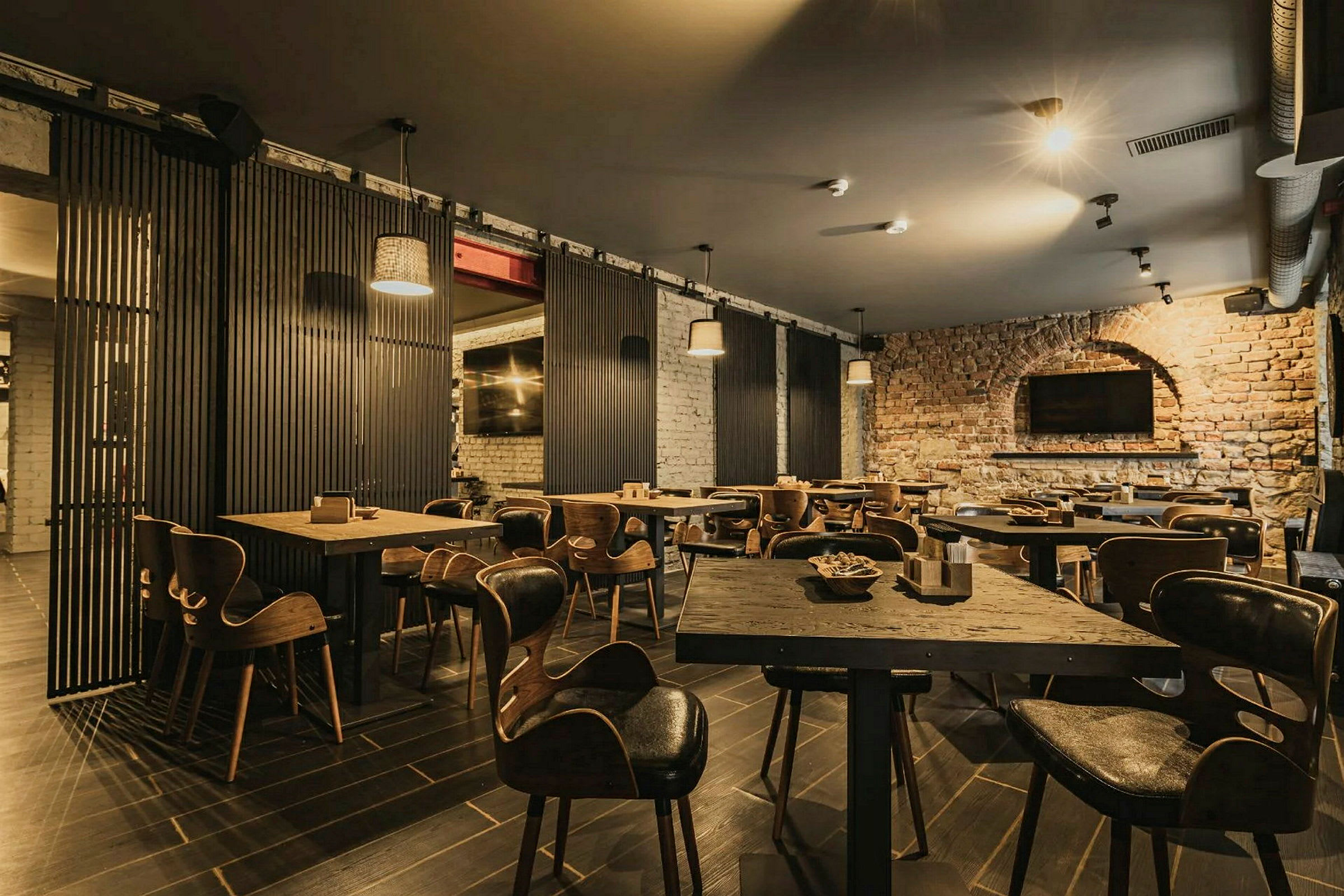 Ravintola, jossa on puupöytiä ja tuoleja sekä tiiliseinät. (Tekoälyn luoma teksti)