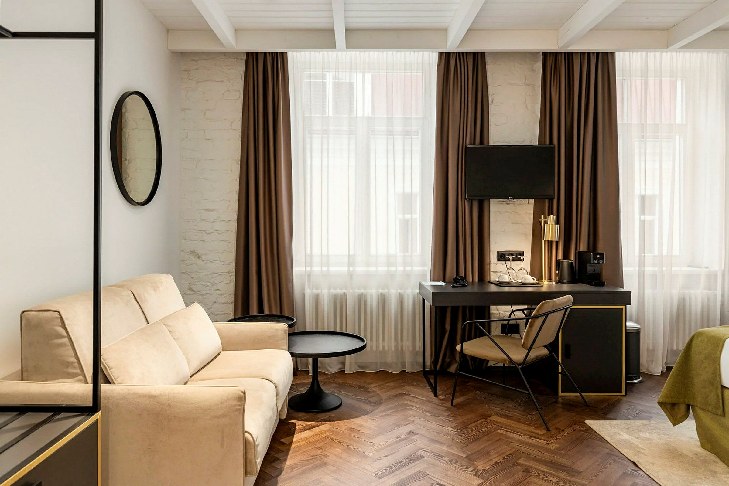 Modernisti sisustettu hotellihuone, jossa on sohva, työpöytä ja televisio. (Tekoälyn luoma teksti)