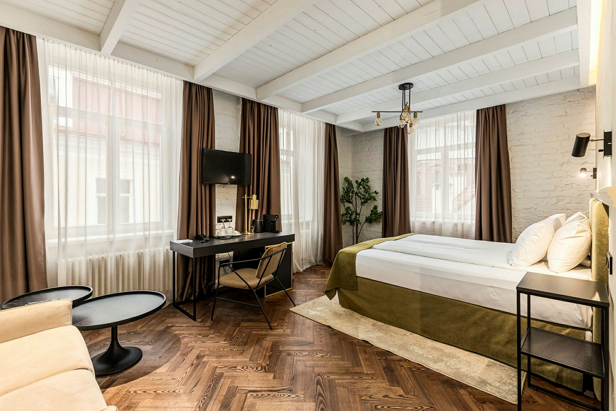 Hotellihuone, jossa on sänky, kirjoituspöytä ja istuinryhmä. (Tekoälyn luoma teksti)