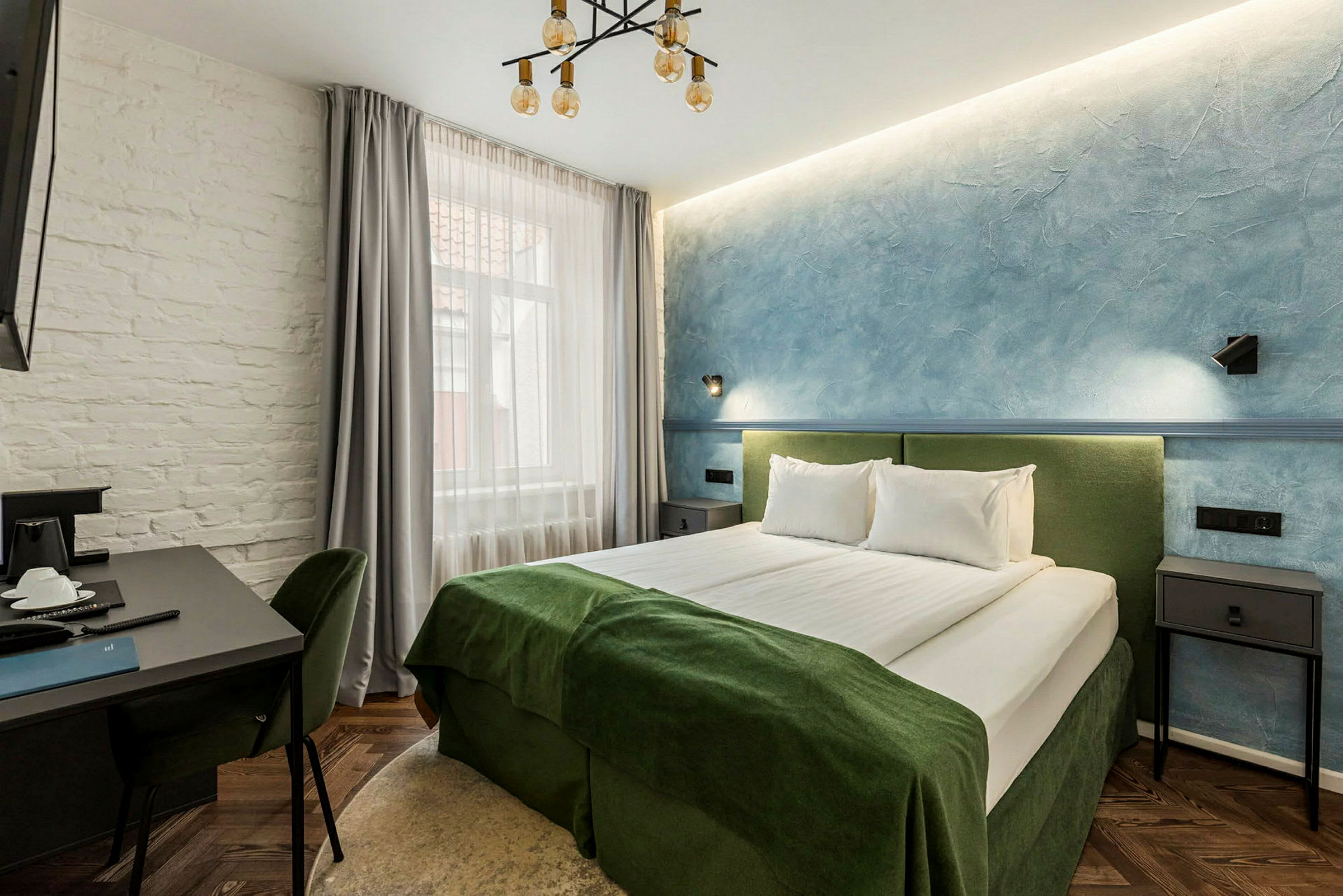 Hotellihuone, jossa parivuode, pöytä ja tuolit. (Tekoälyn luoma teksti)