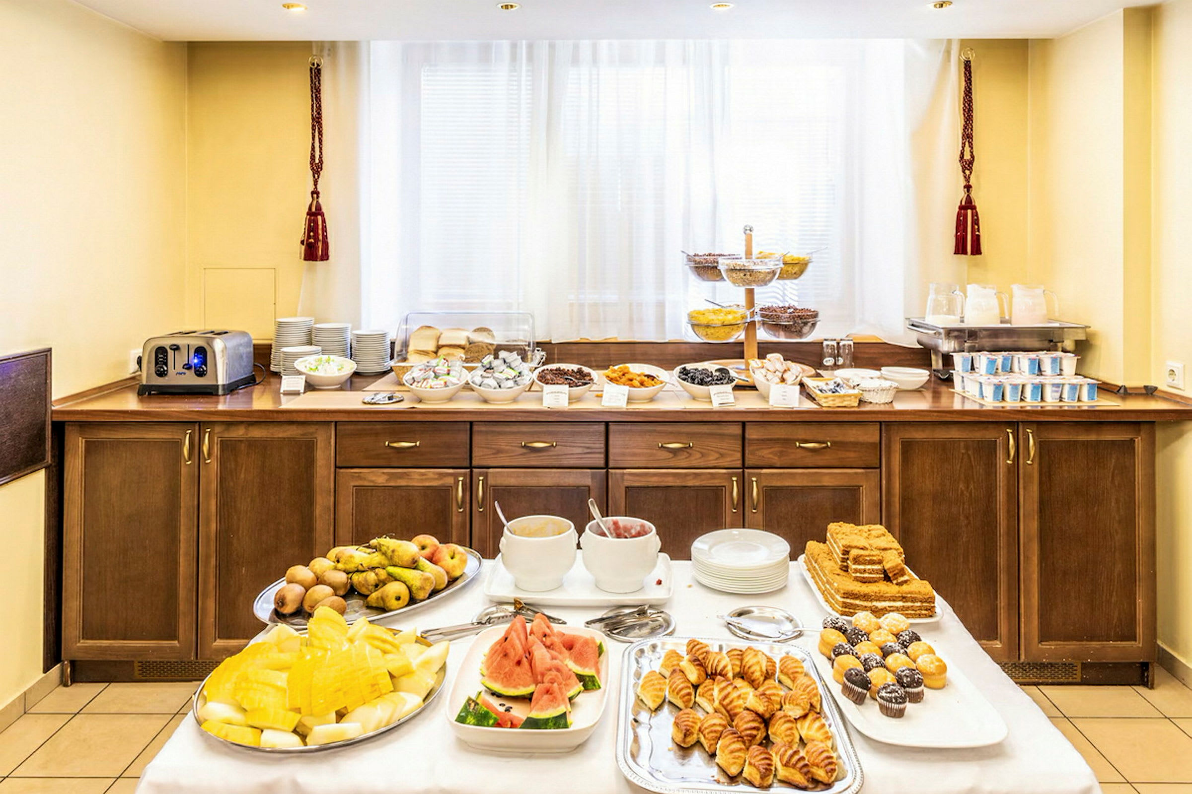 Hotelliaamiainenbuffet eri ruokia, mukaan lukien hedelmät, leivonnaiset ja juomat. (Tekoälyn luoma teksti)