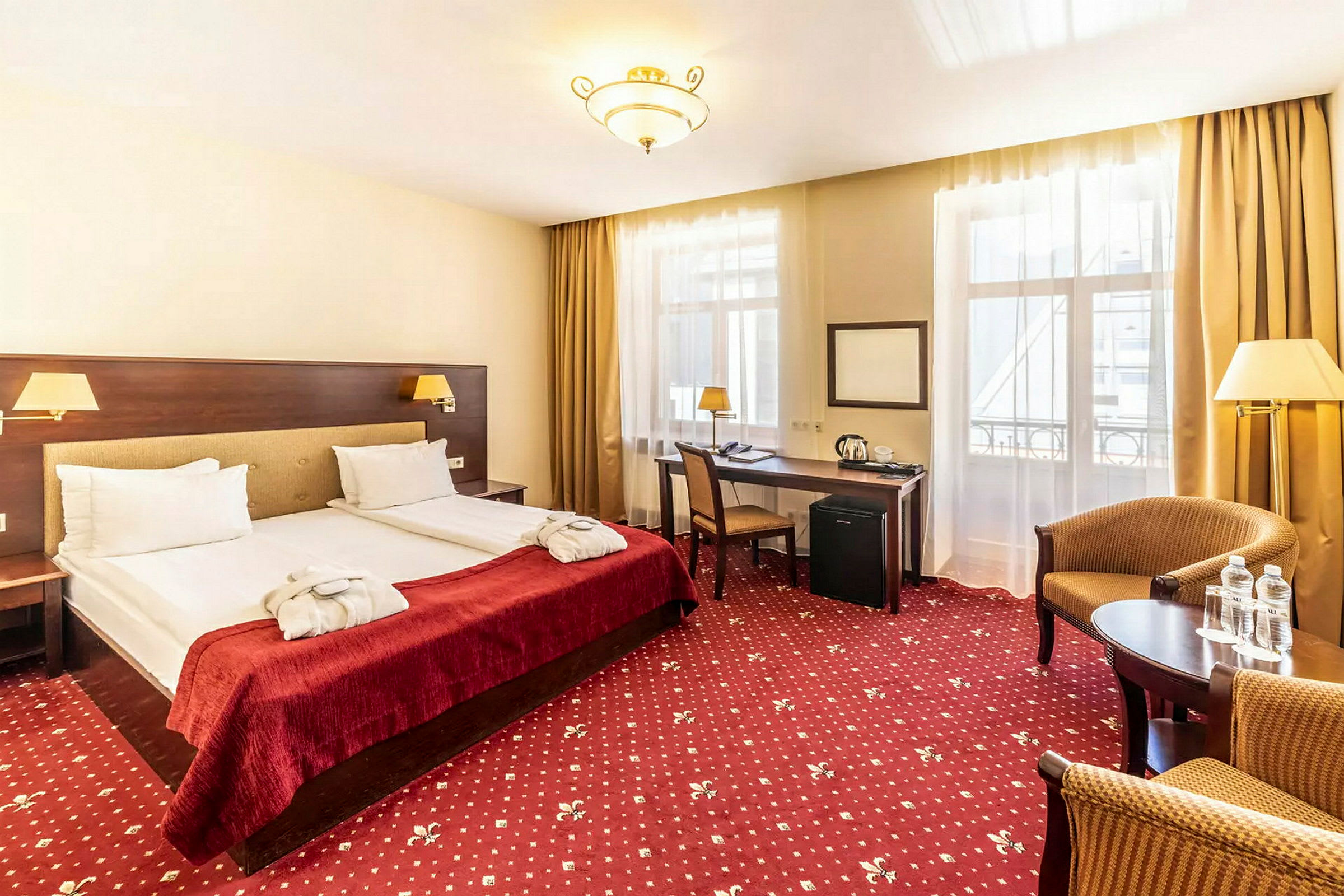 Hotellihuone, jossa kaksi erillistä vuodetta, työpöytä ja oleskelualue. (Tekoälyn luoma teksti)