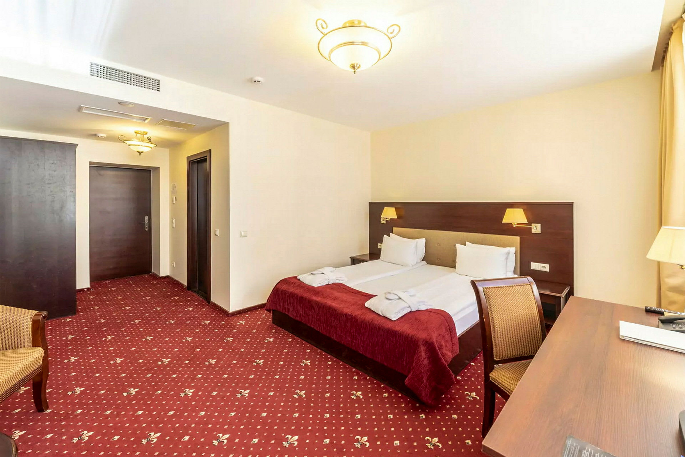 Hotellihuone, jossa on parivuode, kirjoituspöytä ja tuoli. (Tekoälyn luoma teksti)