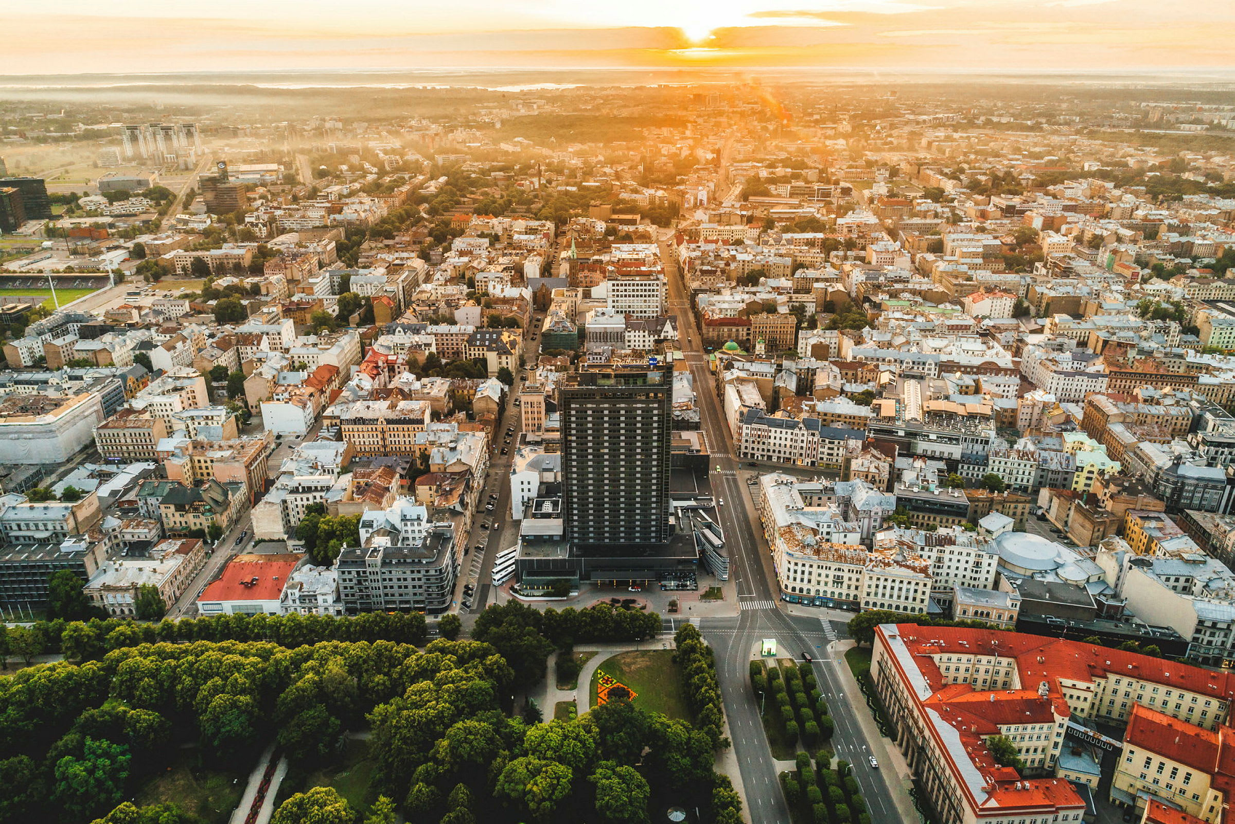 Ilmakuva kaupungista, jossa on rakennuksia, teitä ja puistoja auringonlaskun aikaan. (Tekoälyn luoma teksti)