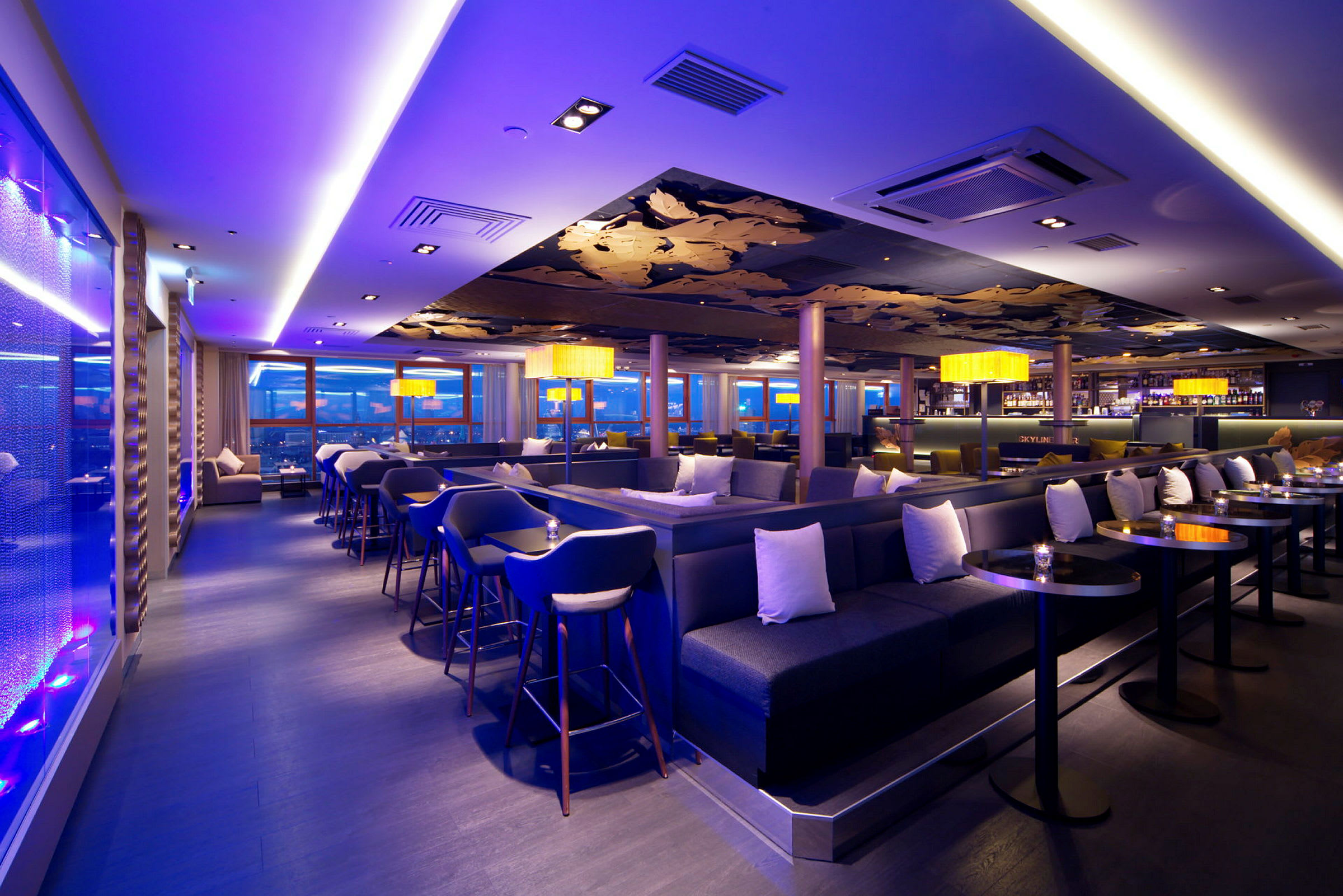Tyylikäs lounge- ja baarialue, jossa on modernit kalusteet, tunnelmallinen valaistus ja suuret panoraamaikkunat. (Tekoälyn luoma teksti)