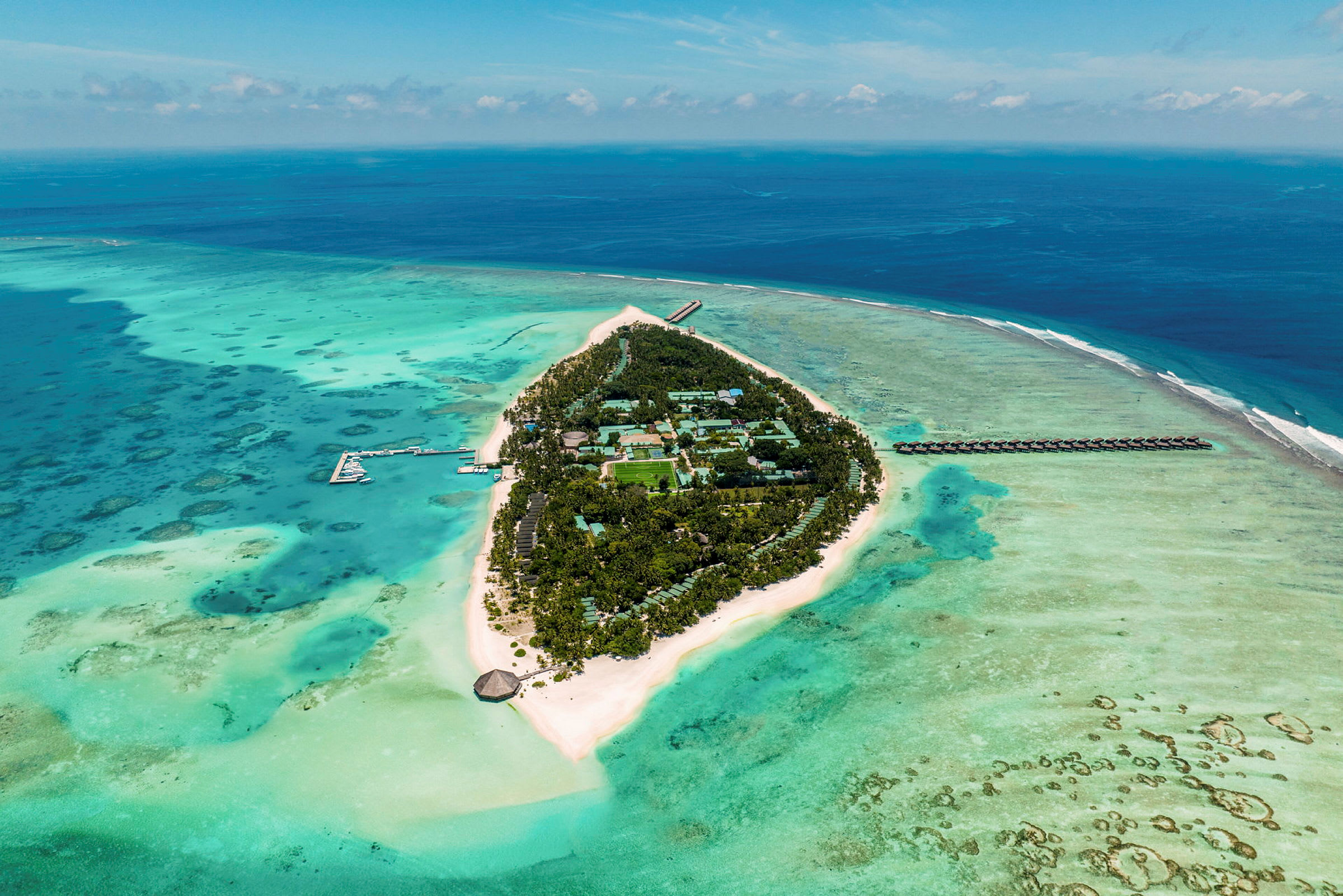 Ilmakuva trooppisesta saaresta, jota ympäröi turkoosi meri, valkoiset hiekkarannat ja vihreä kasvillisuus. (Tekoälyn luoma teksti)