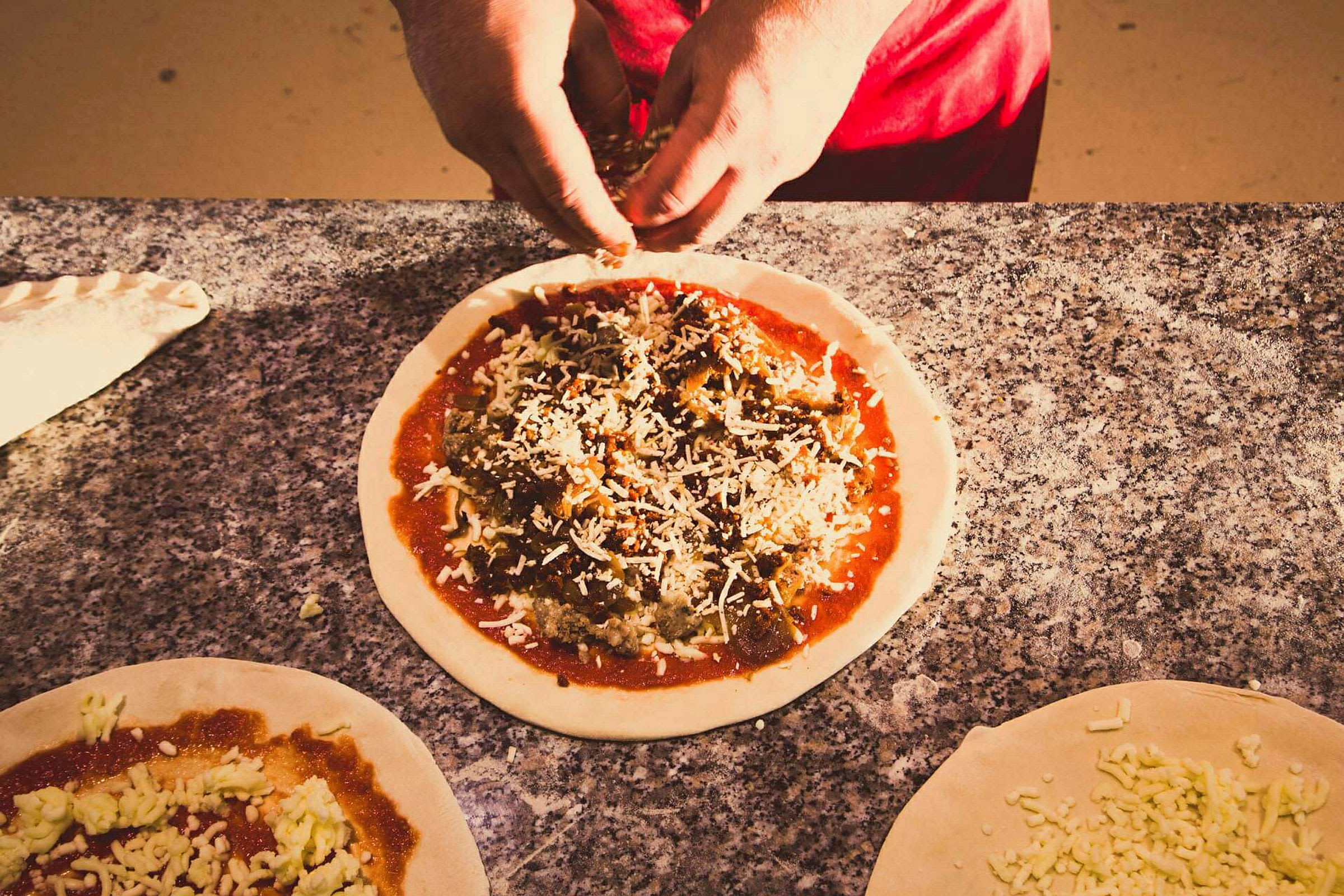 Henkilö valmistelee pizzaa täytteiden kanssa marmorialustalla. (Tekoälyn luoma teksti)