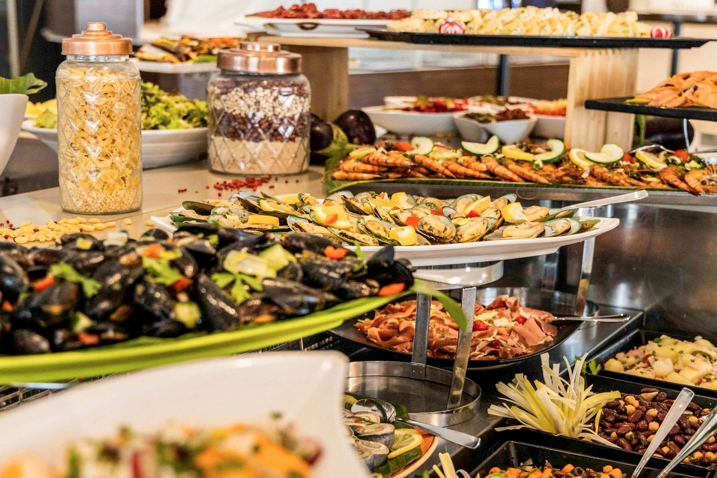 Buffet, jossa on erilaisia ruokalajeja, kuten simpukoita, katkarapuja ja pastasalaattia. (Tekoälyn luoma teksti)