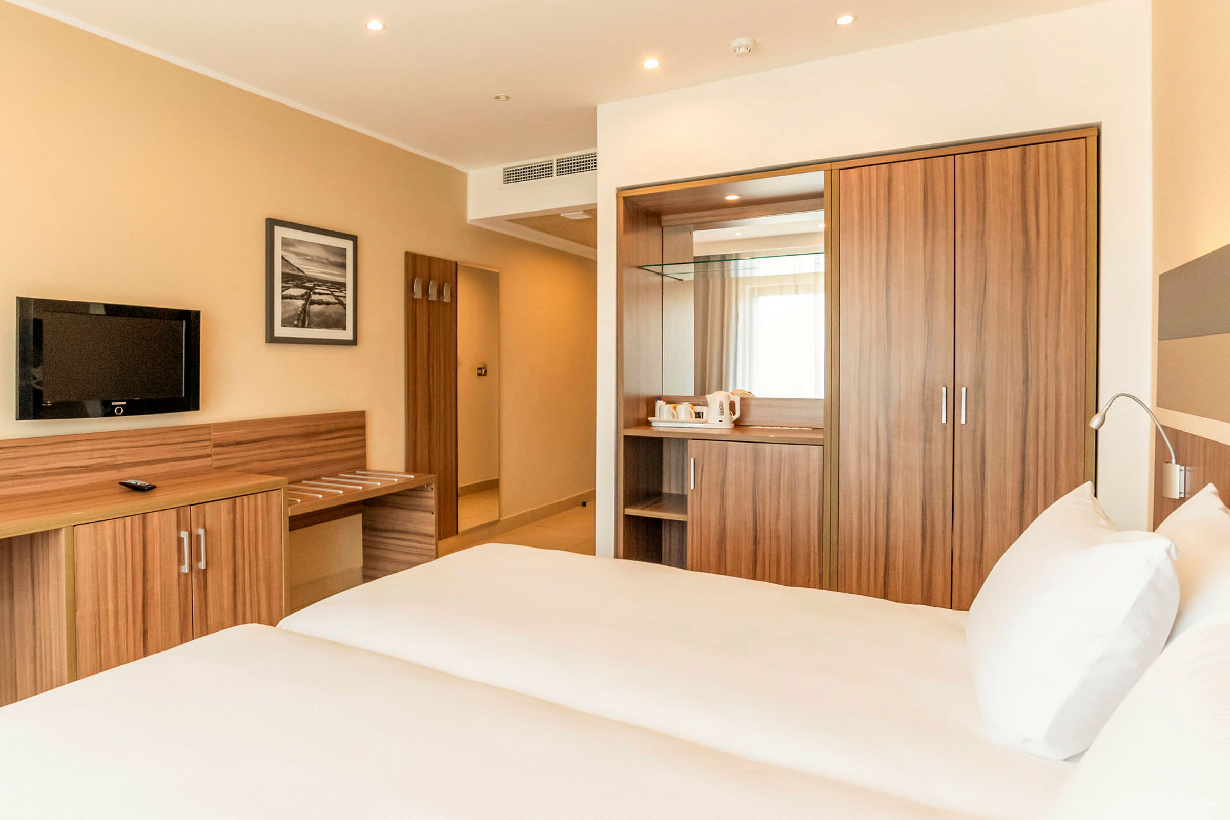 Hotellihuone, jossa kaksi sänkyä, puinen työpöytä ja vaatekaappi. (Tekoälyn luoma teksti)