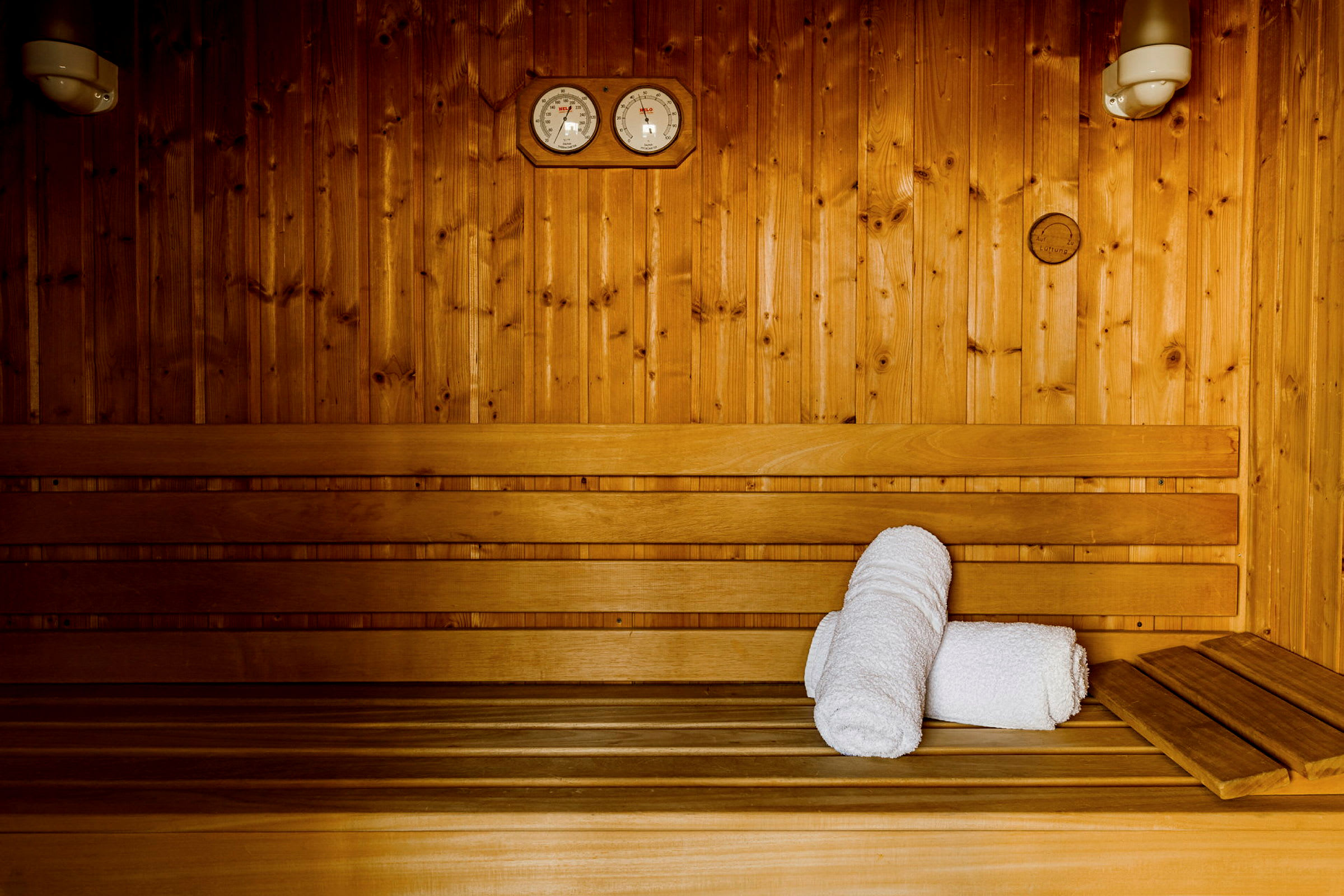 Puutarhassa sauna, jossa on penkkejä ja kaksi rullattua valkoista pyyhettä. (Tekoälyn luoma teksti)
