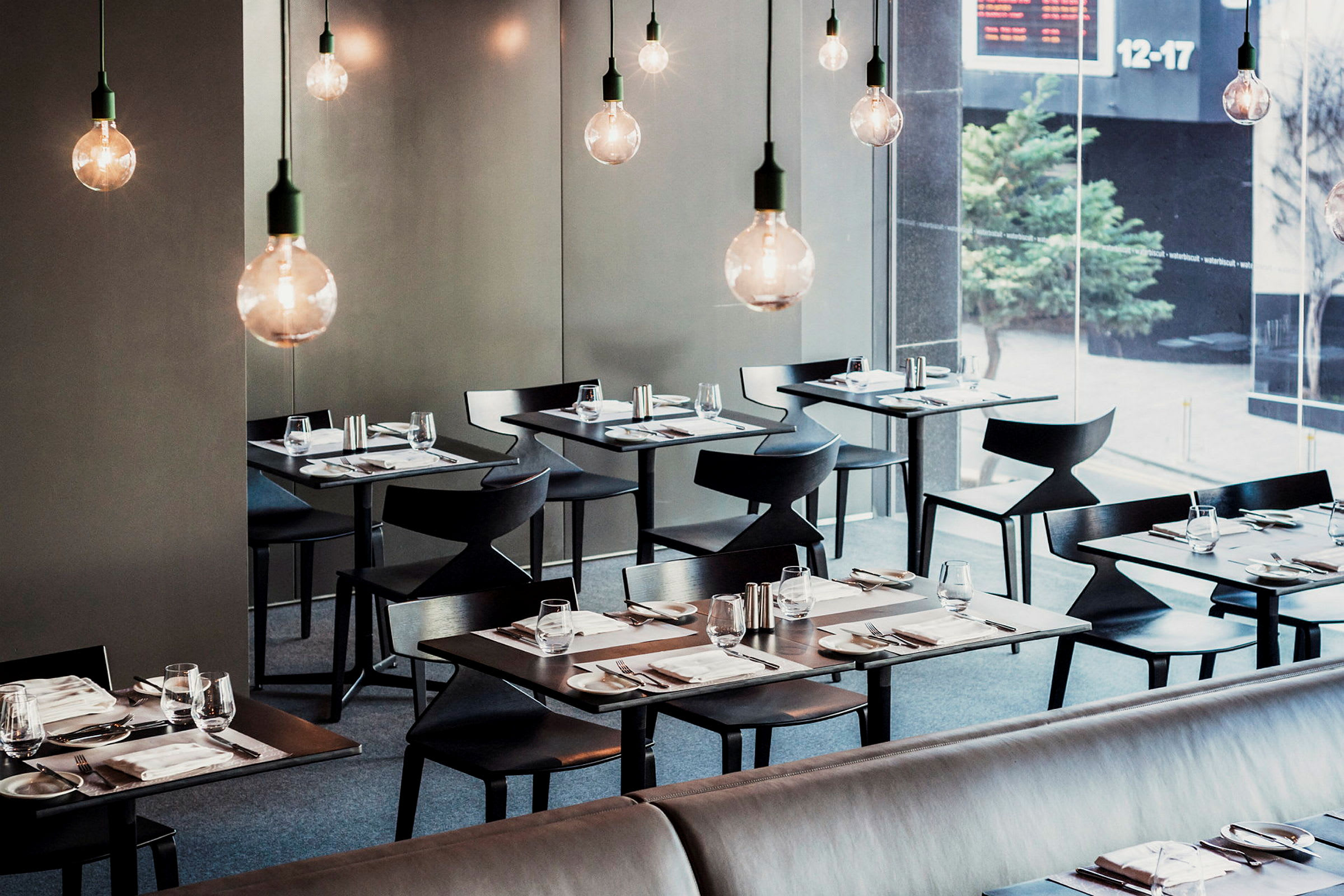 Moderni ravintola, jossa tyylikkäästi katetut pöydät ja roikkuvat lamput. (Tekoälyn luoma teksti)