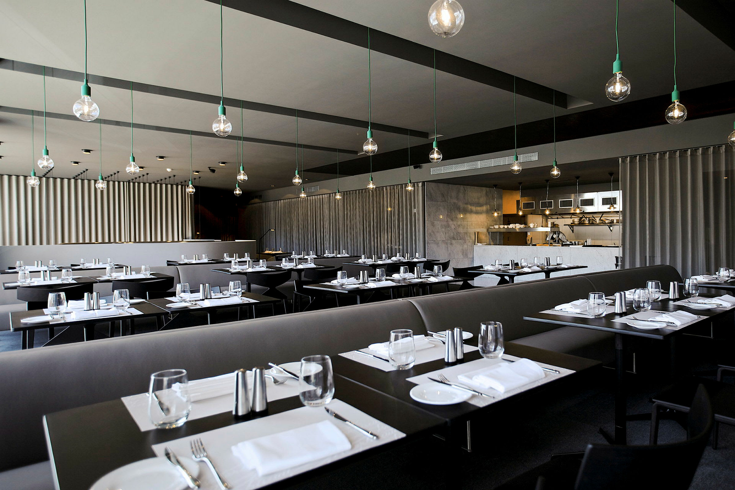 Moderni ravintola, jossa on tummat pöydät, katettu ruokailua varten ja tyylikäs kattovalaistus. (Tekoälyn luoma teksti)