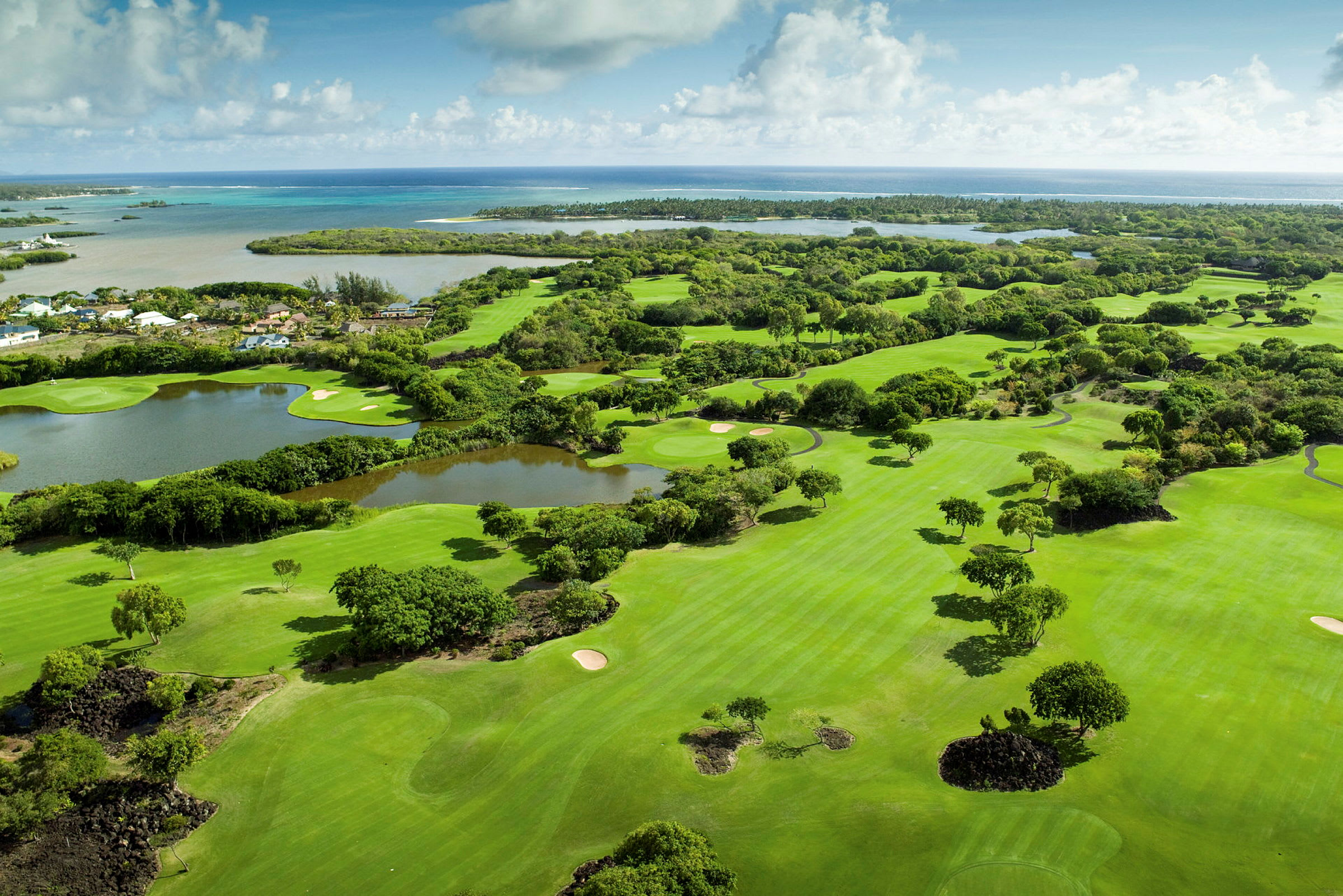 Ilmakuva golfkentästä, jota ympäröi vehreys, ja taustalla näkyy meri. (Tekoälyn luoma teksti)