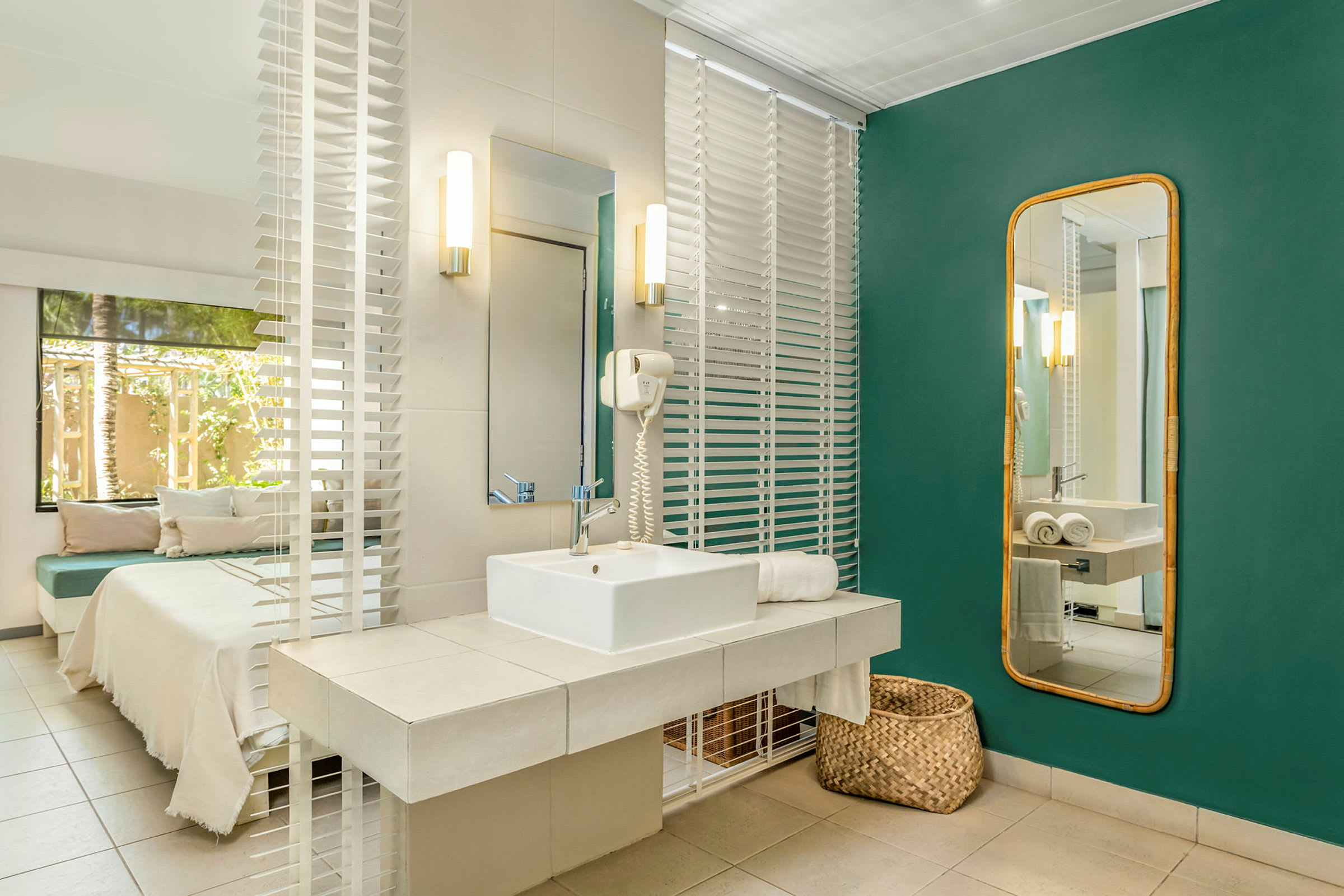 Moderni kylpyhuone, jossa pesuallas, peili ja vihreät seinät. Sänky ja ulkotila näkyvät aukosta. (Tekoälyn luoma teksti)
