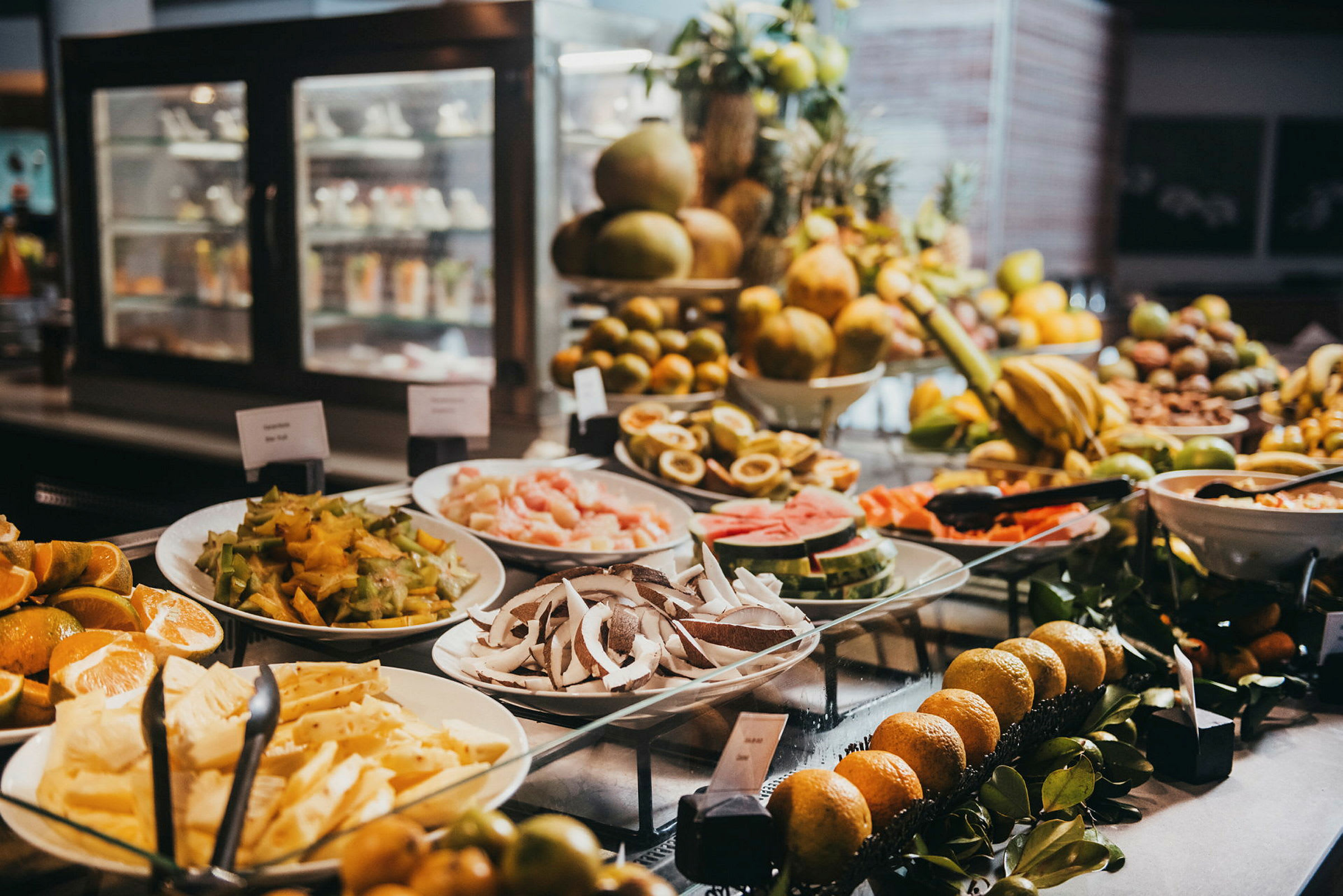 Buffet-pöytä, jossa on erilaisia trooppisia hedelmiä ja viipaleita lautasilla. (Tekoälyn luoma teksti)