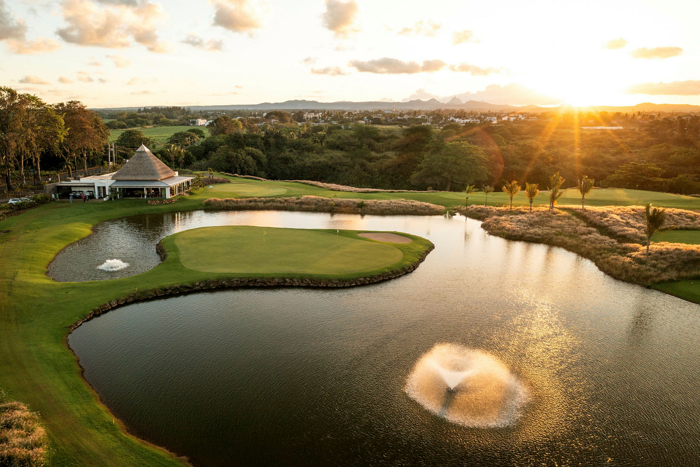 Golfkenttä, jossa lampi ja suihkulähde auringonlaskun aikaan. (Tekoälyn luoma teksti)