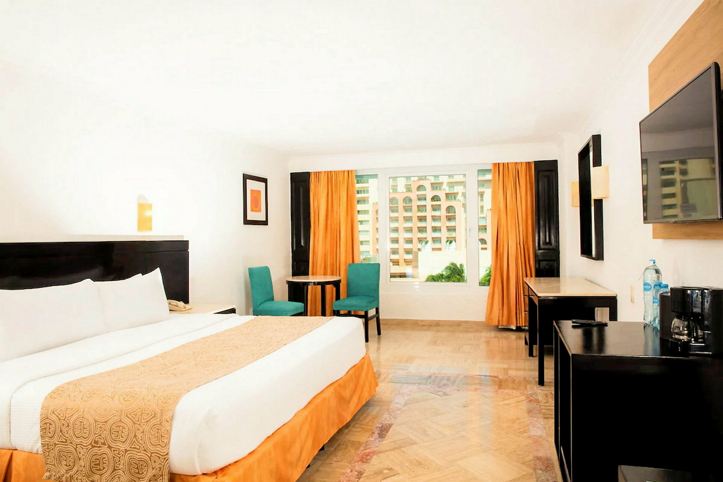 Hotellihuone, jossa on suuri sänky, kaksi tuolia, pöytä ja ikkuna oransseilla verhoilla. (Tekoälyn luoma teksti)