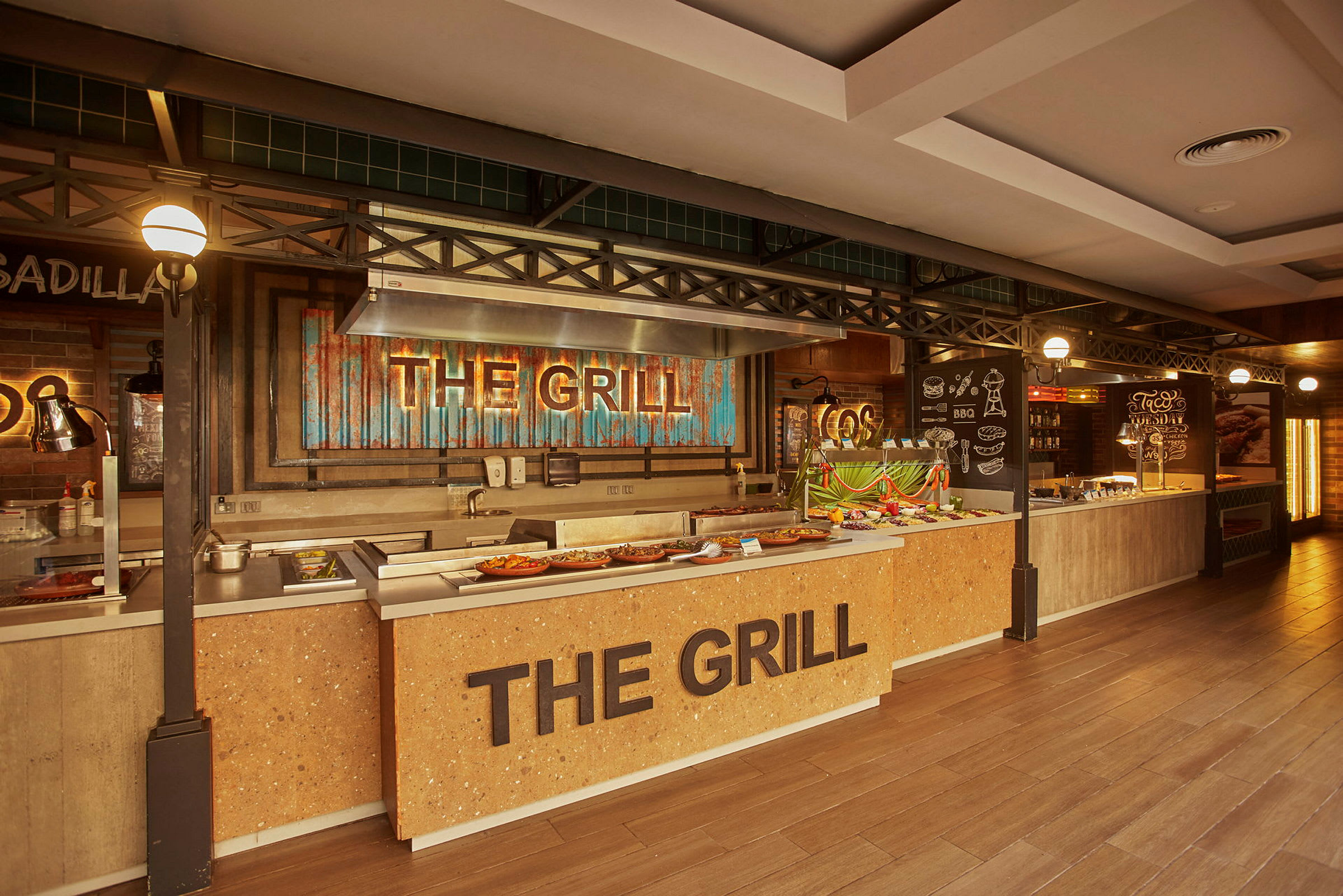 Buffet-alue, jossa on grillausasema nimeltä 'The Grill' ja ruokatarjoiluja. (Tekoälyn luoma teksti)
