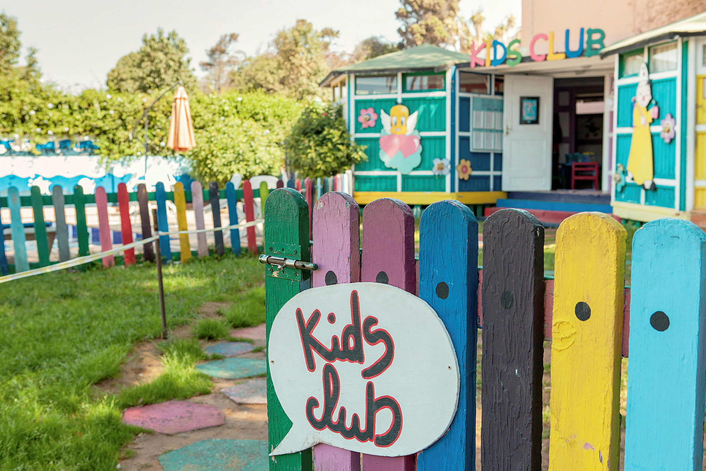 Leikkipaikka, jossa on värikäs aita ja kyltti "Kids Club". (Tekoälyn luoma teksti)