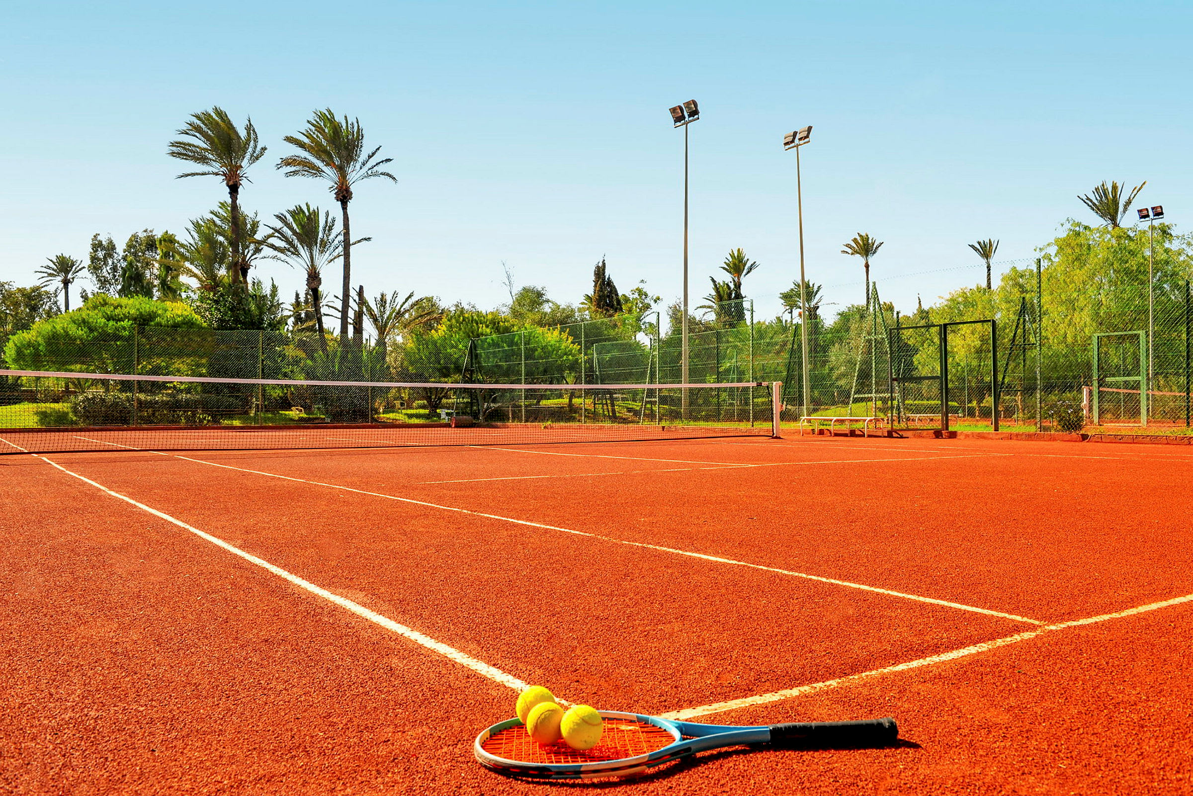Tenniskenttä, jossa maila ja pallot maassa. (Tekoälyn luoma teksti)