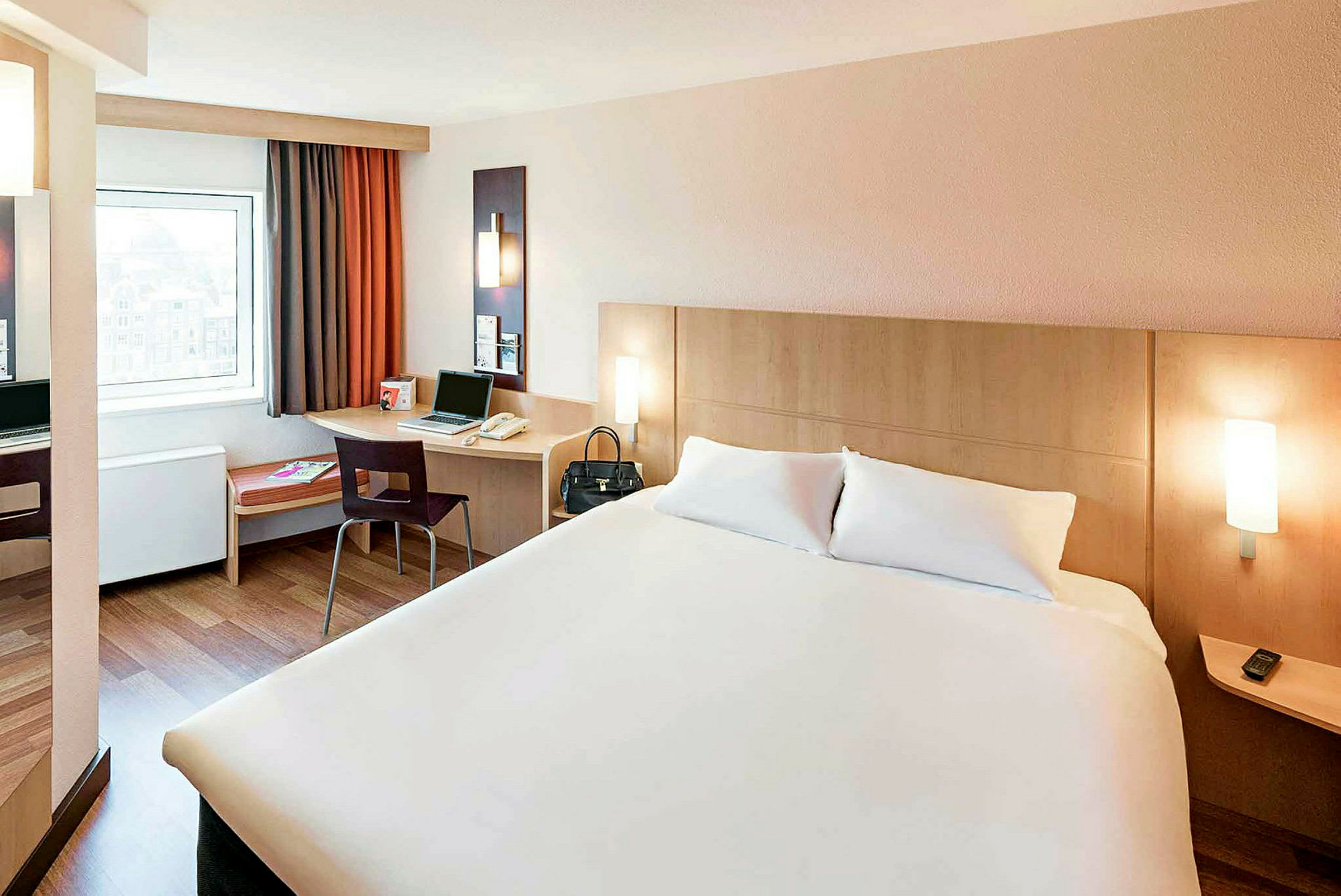 Hotellihuone, jossa on parivuode, työpöytä tuolilla ja ikkuna. (Tekoälyn luoma teksti)