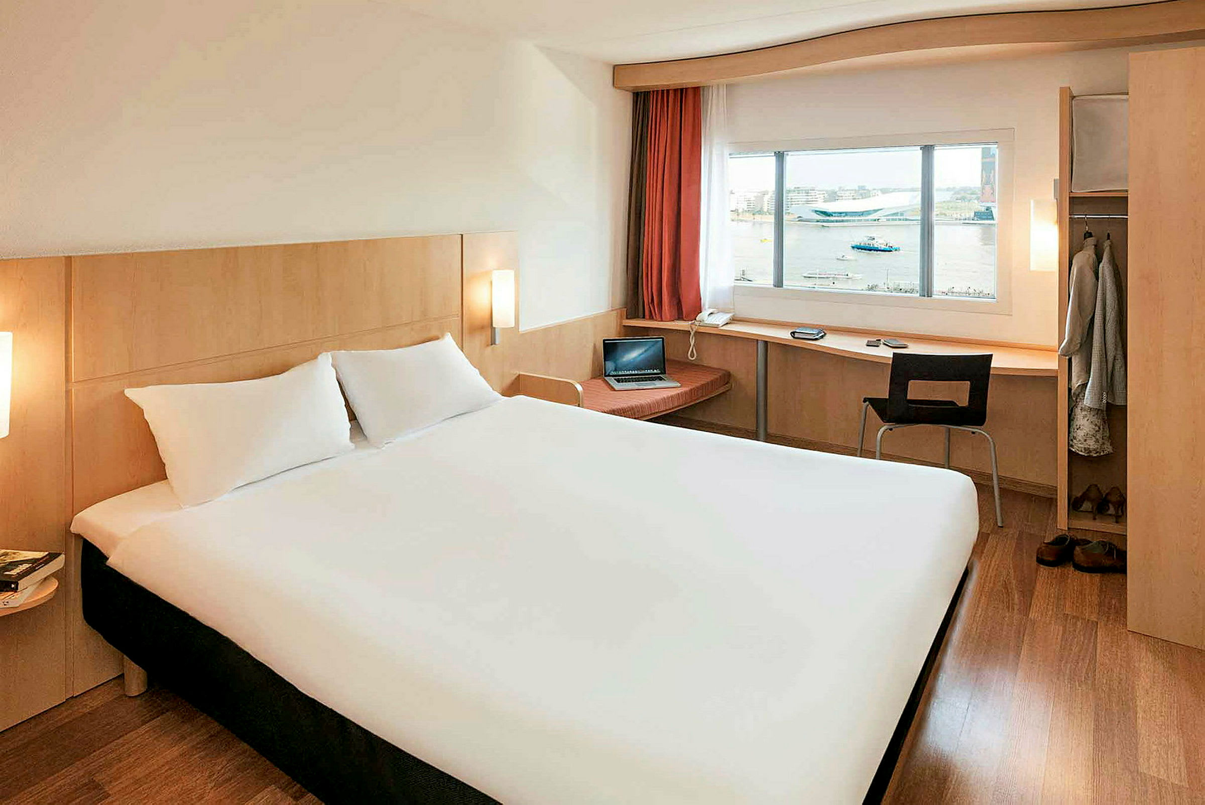 Hotellihuone, jossa on suuri sänky, kirjoituspöytä ikkunan ääressä ja vaatekaappi. (Tekoälyn luoma teksti)