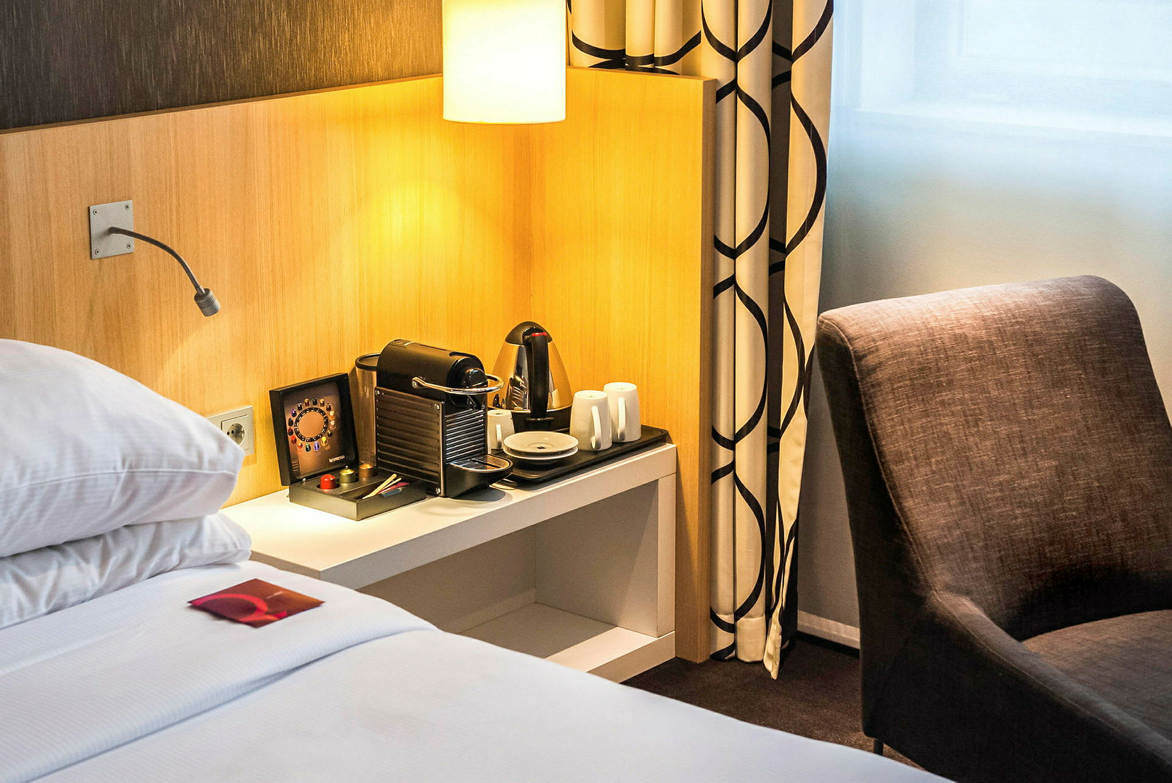 Hotellihuone, jossa sänky, kahvikone ja tuoli. (Tekoälyn luoma teksti)