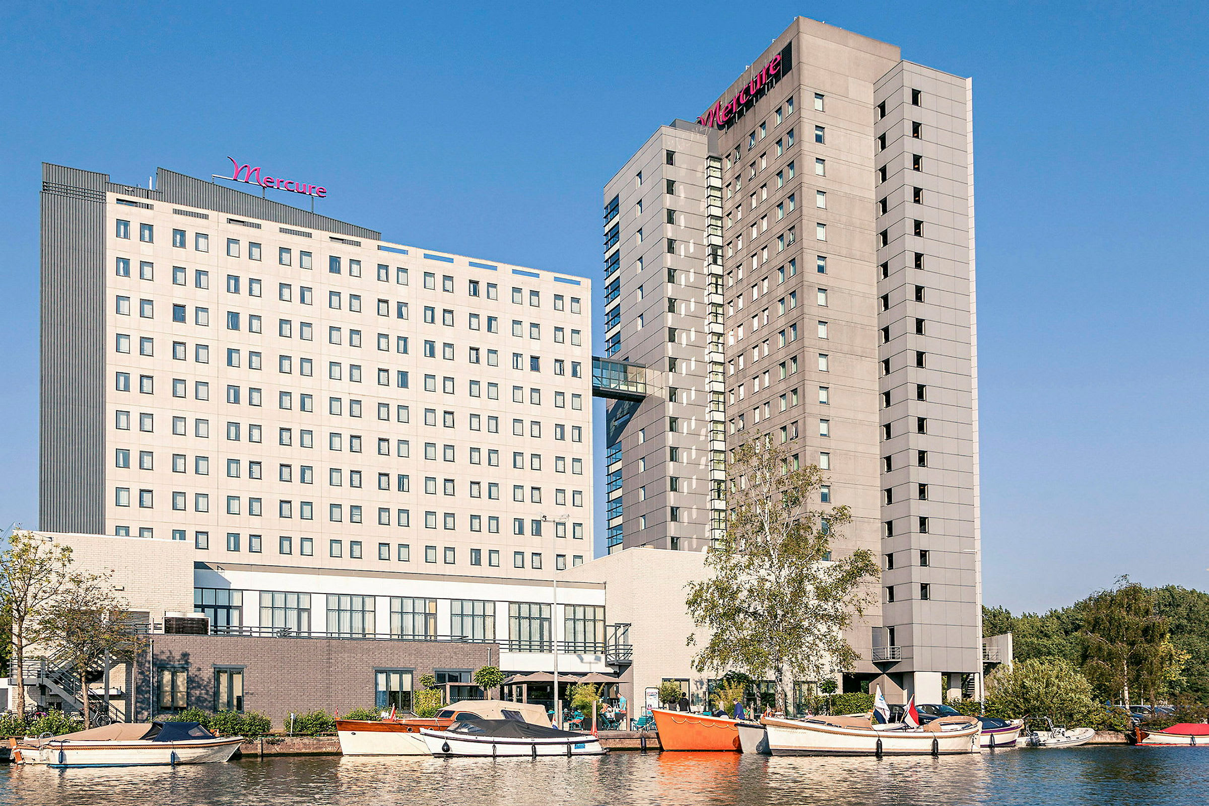 Kuva hotellirakennuksista, etualalla veneitä ja vettä. (Tekoälyn luoma teksti)