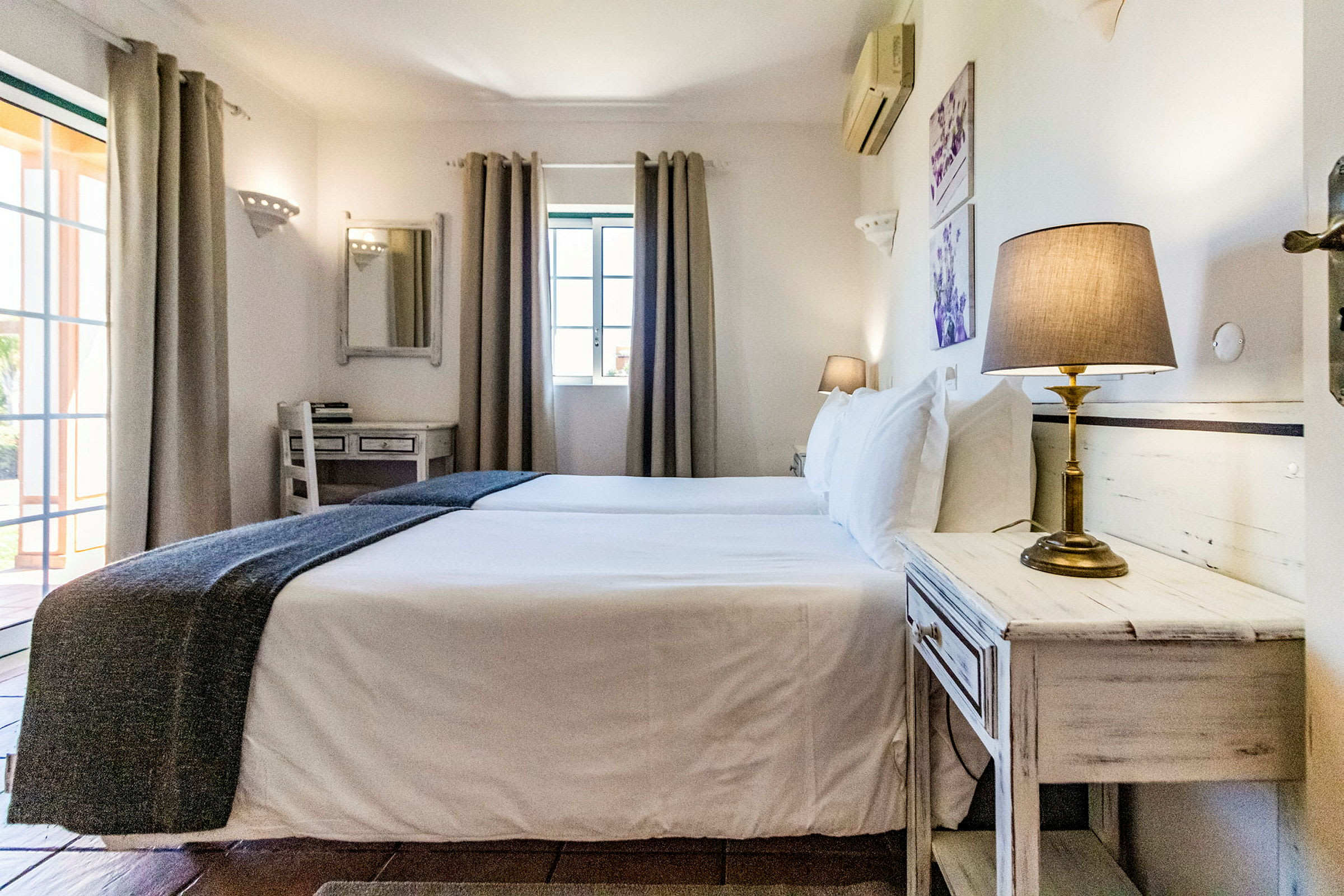 Makuuhuone, jossa kaksi erillistä sänkyä, yöpöytä ja lamput. (Tekoälyn luoma teksti)