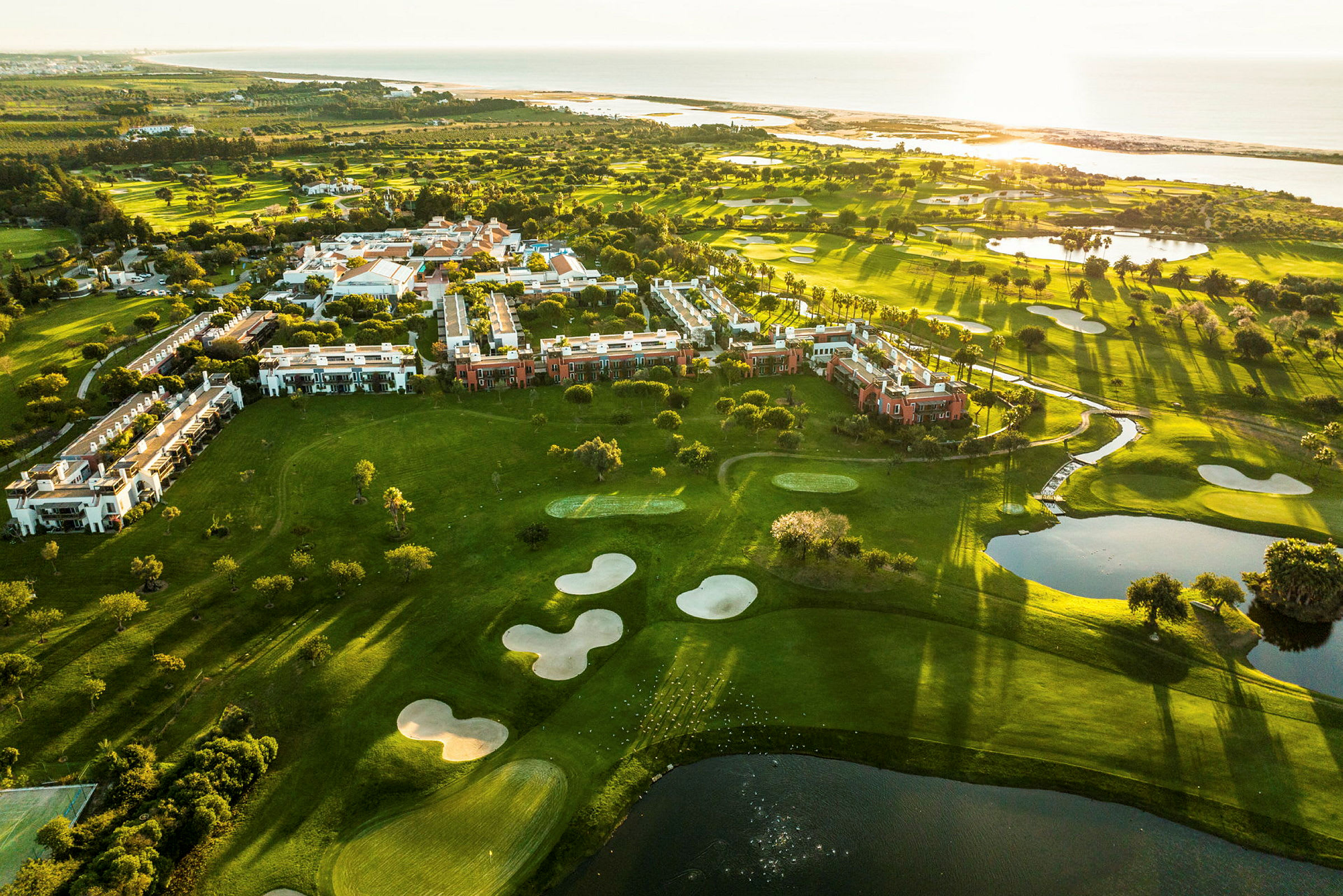 Ilmakuva vehreistä alueista, joissa on rakennuksia ja golfkenttiä meren rannalla. (Tekoälyn luoma teksti)