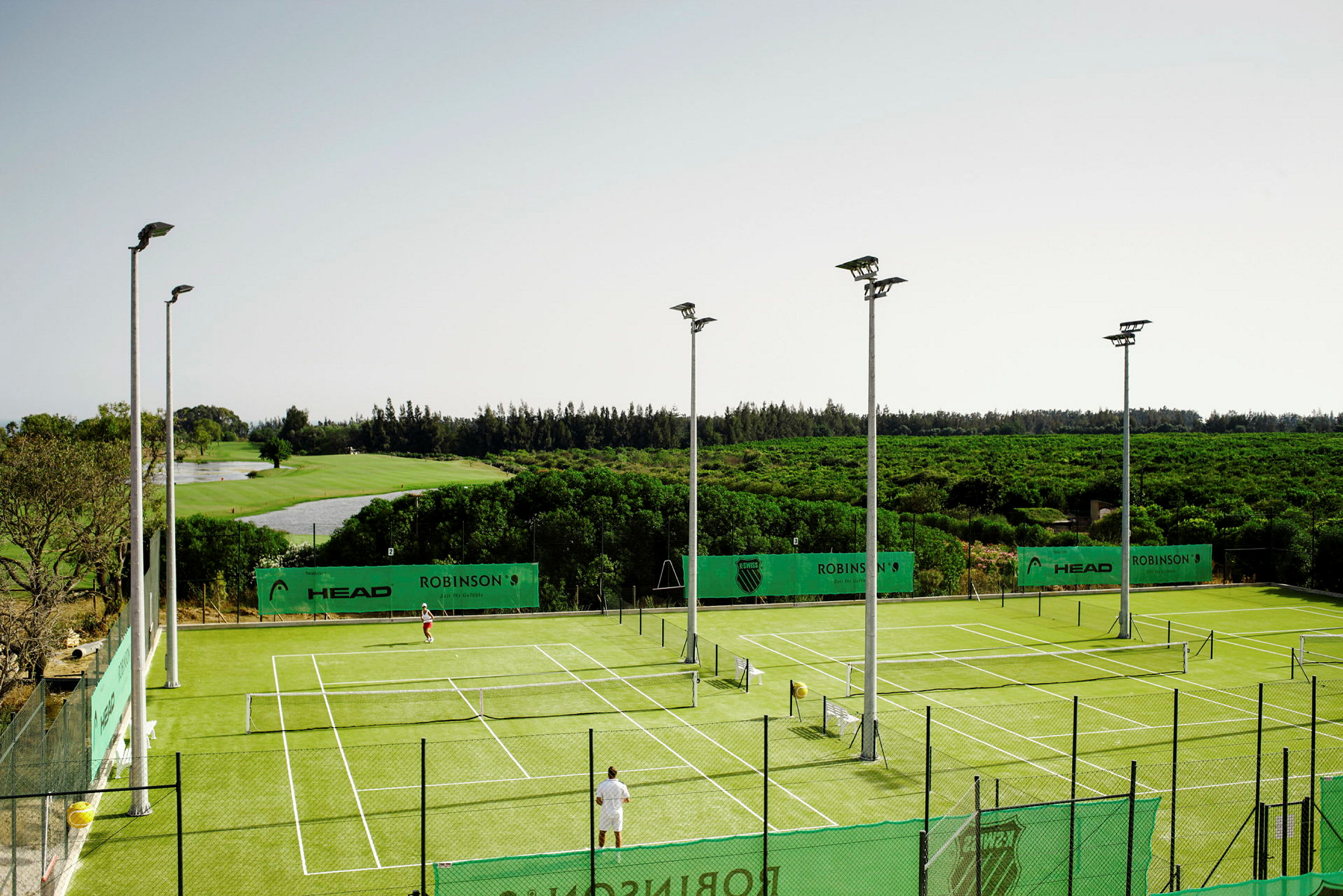 Tenniskentät vihreällä alustalla, ympärillä viheraluetta. (Tekoälyn luoma teksti)
