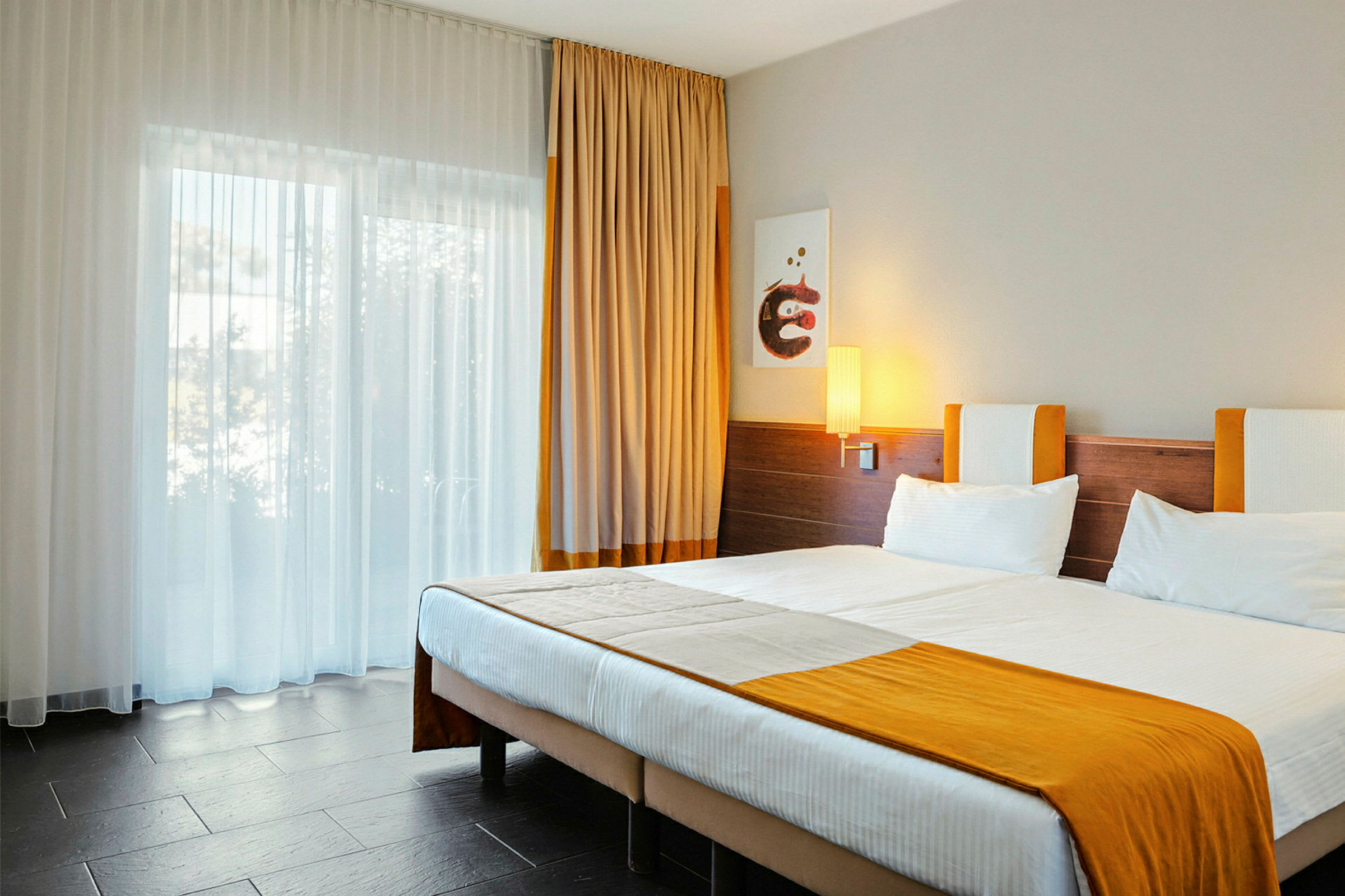 Hotellihuone, jossa on parivuode ja oransseja yksityiskohtia. (Tekoälyn luoma teksti)