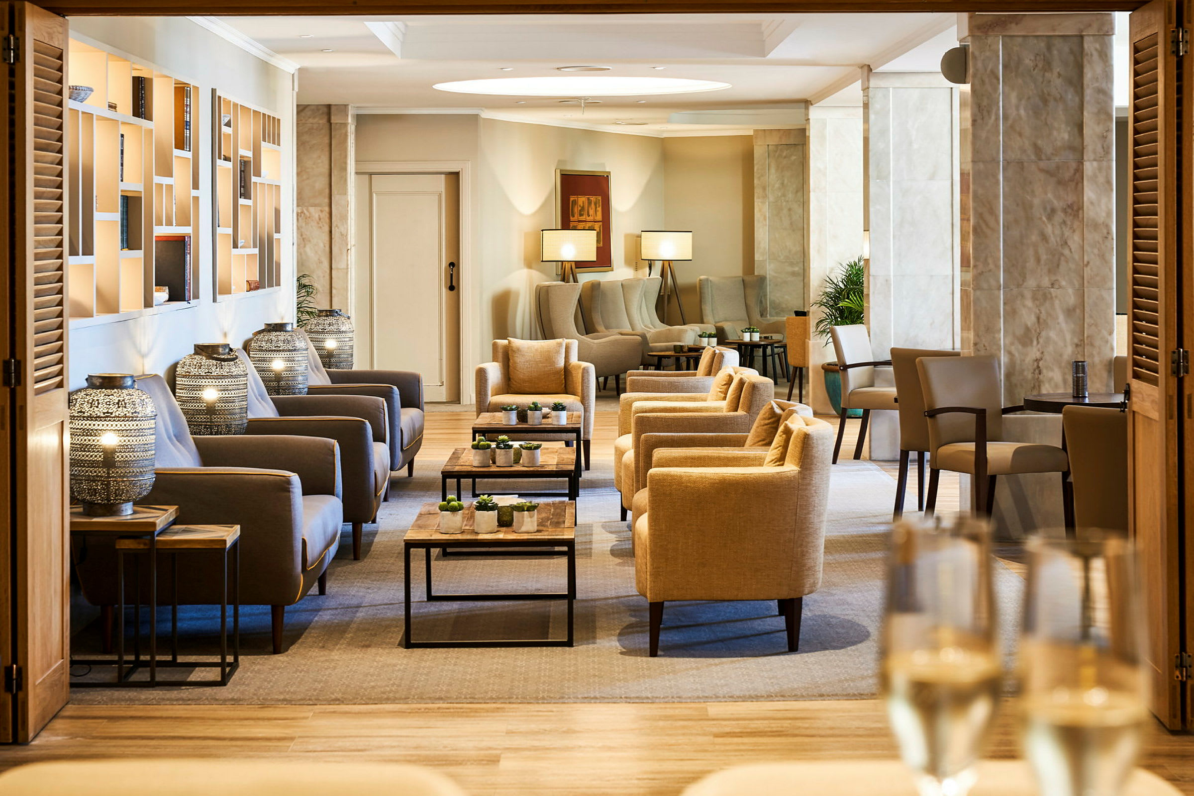 Tyylikäs lounge-alue beigeillä ja harmailla istuinkalusteilla sekä moderneilla koristeellisilla yksityiskohdilla. (Tekoälyn luoma teksti)