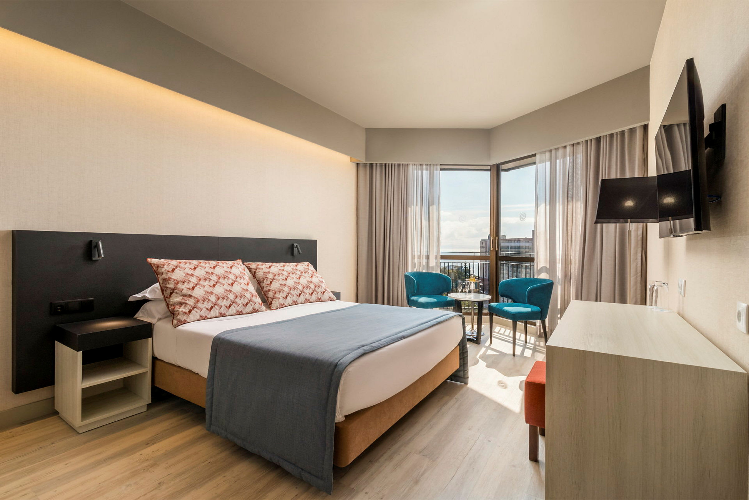Moderni hotellihuone, jossa parivuode, oleskelutila ja näkymä. (Tekoälyn luoma teksti)