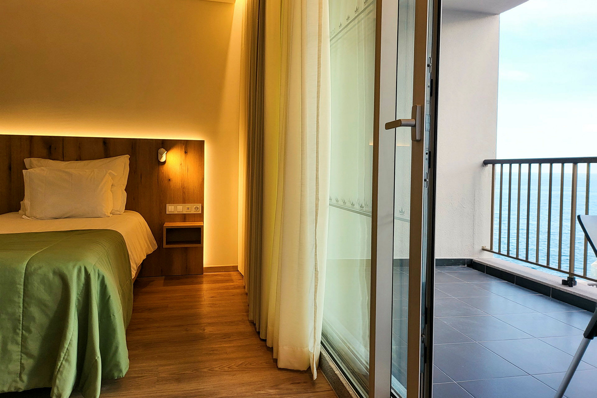 Hotellihuone, jossa sänky ja parveke merinäkymällä. (Tekoälyn luoma teksti)