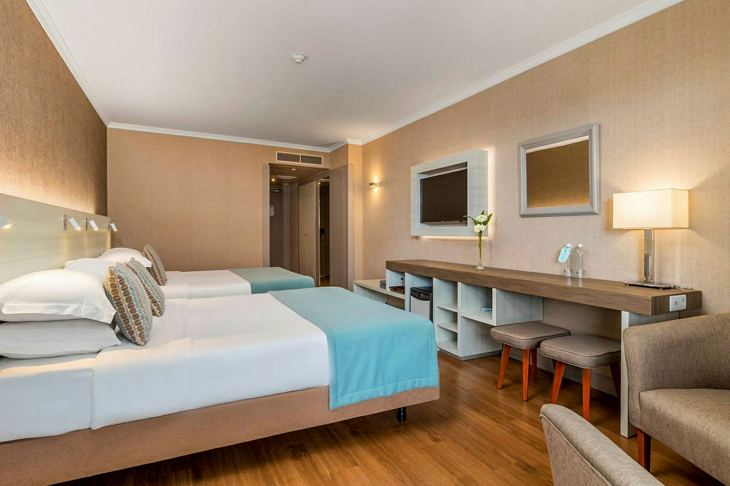 Hotellihuone, jossa kaksi erillistä vuodetta, työtila ja istumakalusteet. (Tekoälyn luoma teksti)