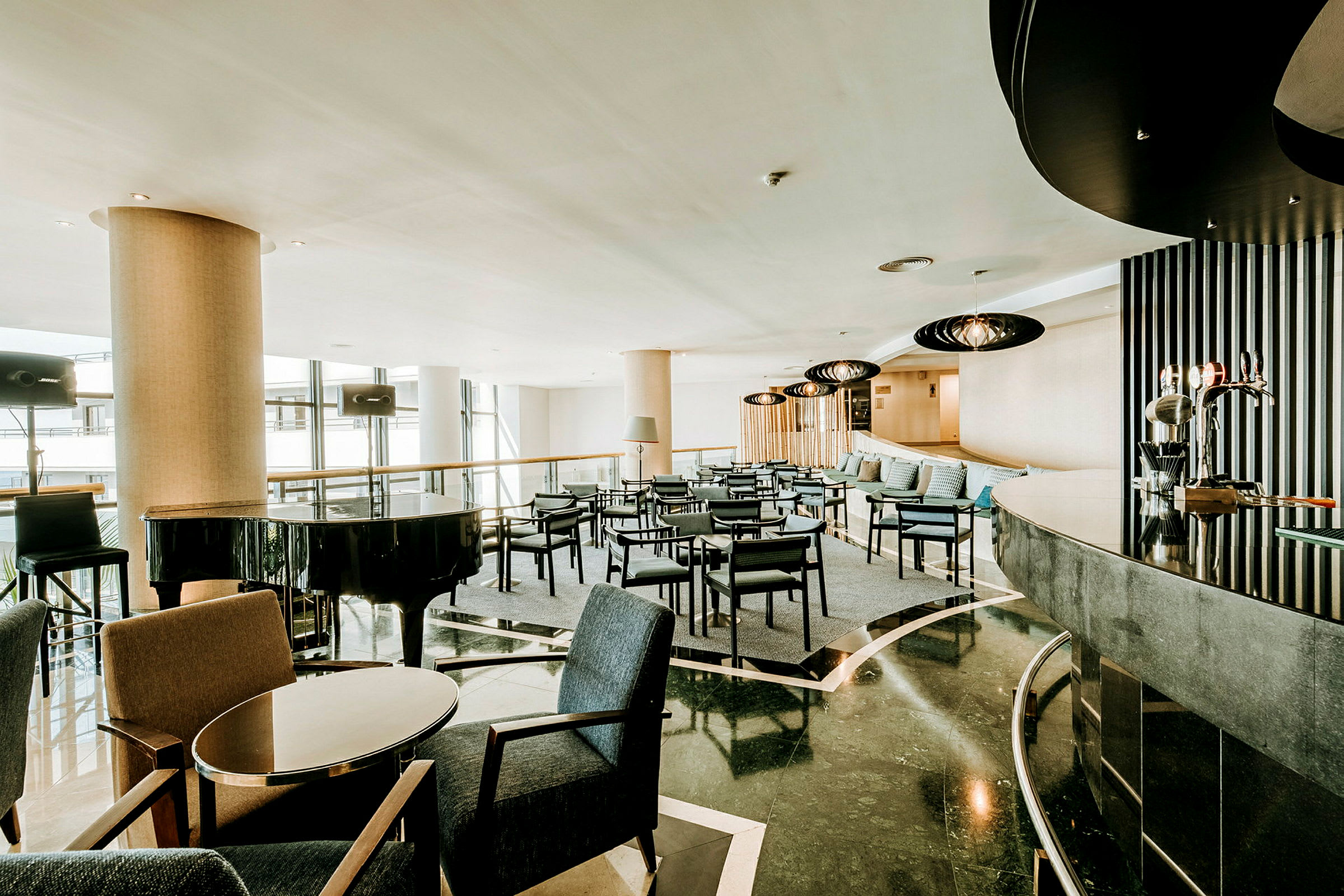 Moderni hotelliaula, jossa istumaryhmiä ja musta flyygeli. (Tekoälyn luoma teksti)