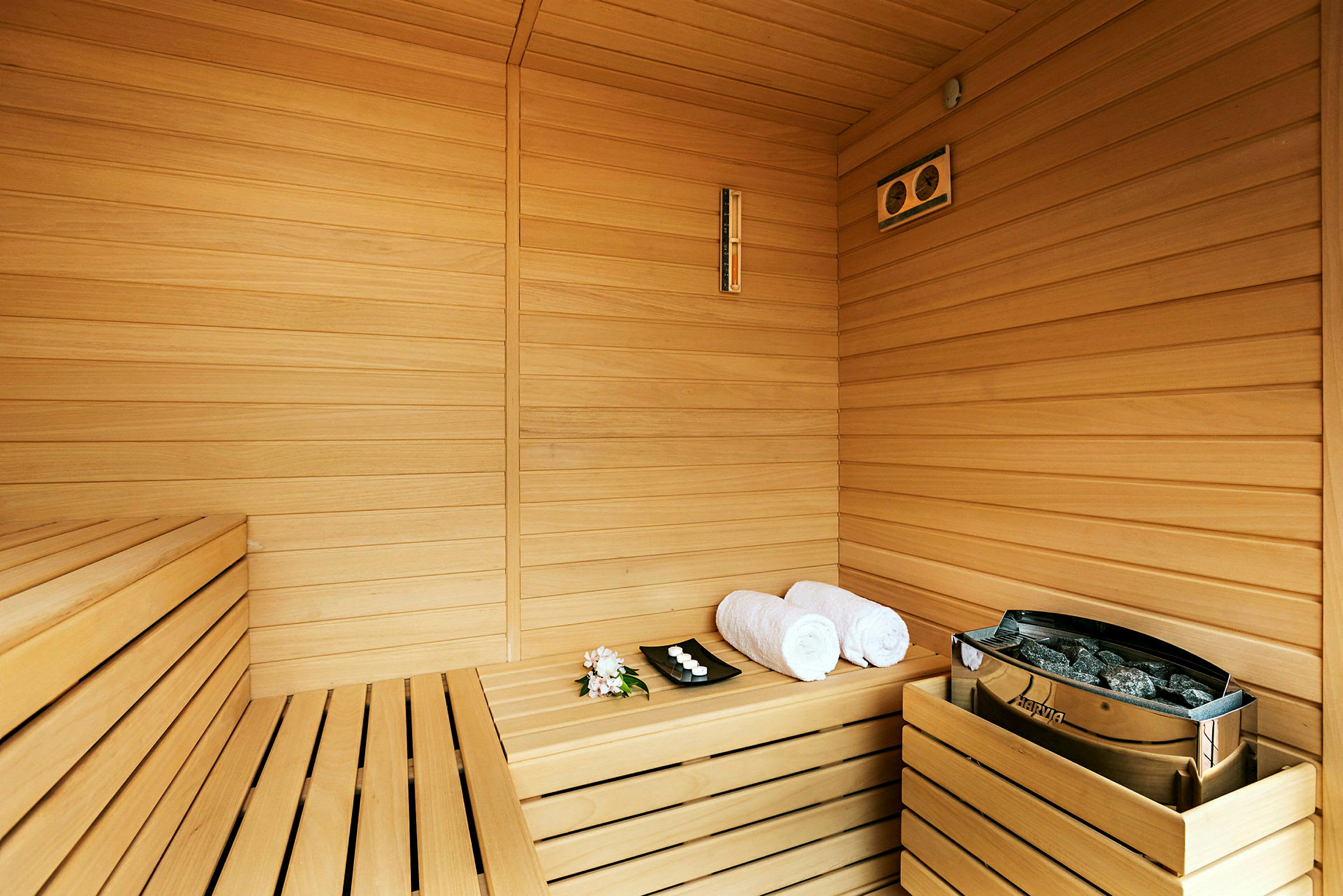Sauna, jossa puupaneelit, kaksi pyyhettä ja tarjotin pienillä kynttilöillä. (Tekoälyn luoma teksti)