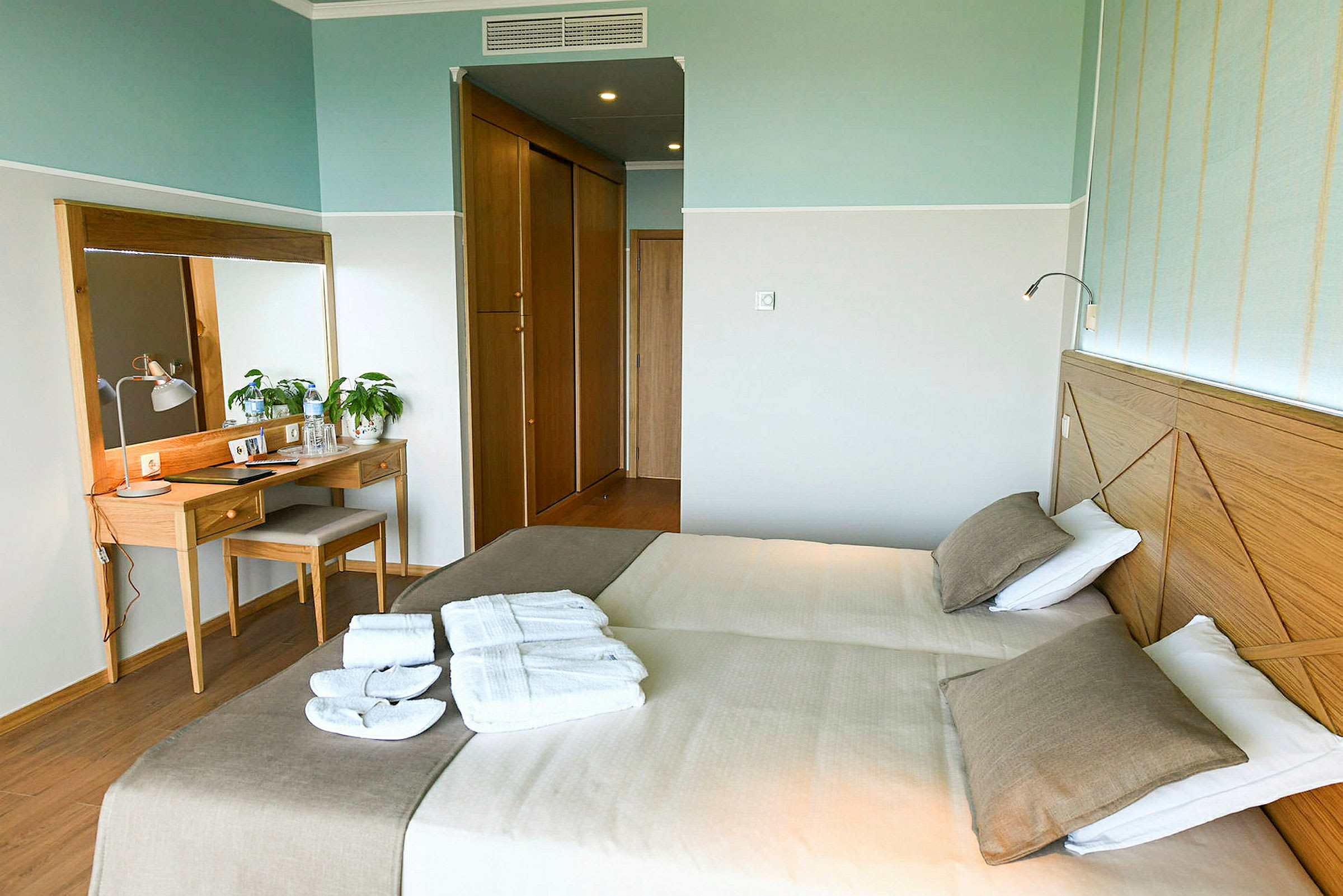 Hotellihuone, jossa kaksi erillistä vuodetta, peili ja kirjoituspöytä. (Tekoälyn luoma teksti)