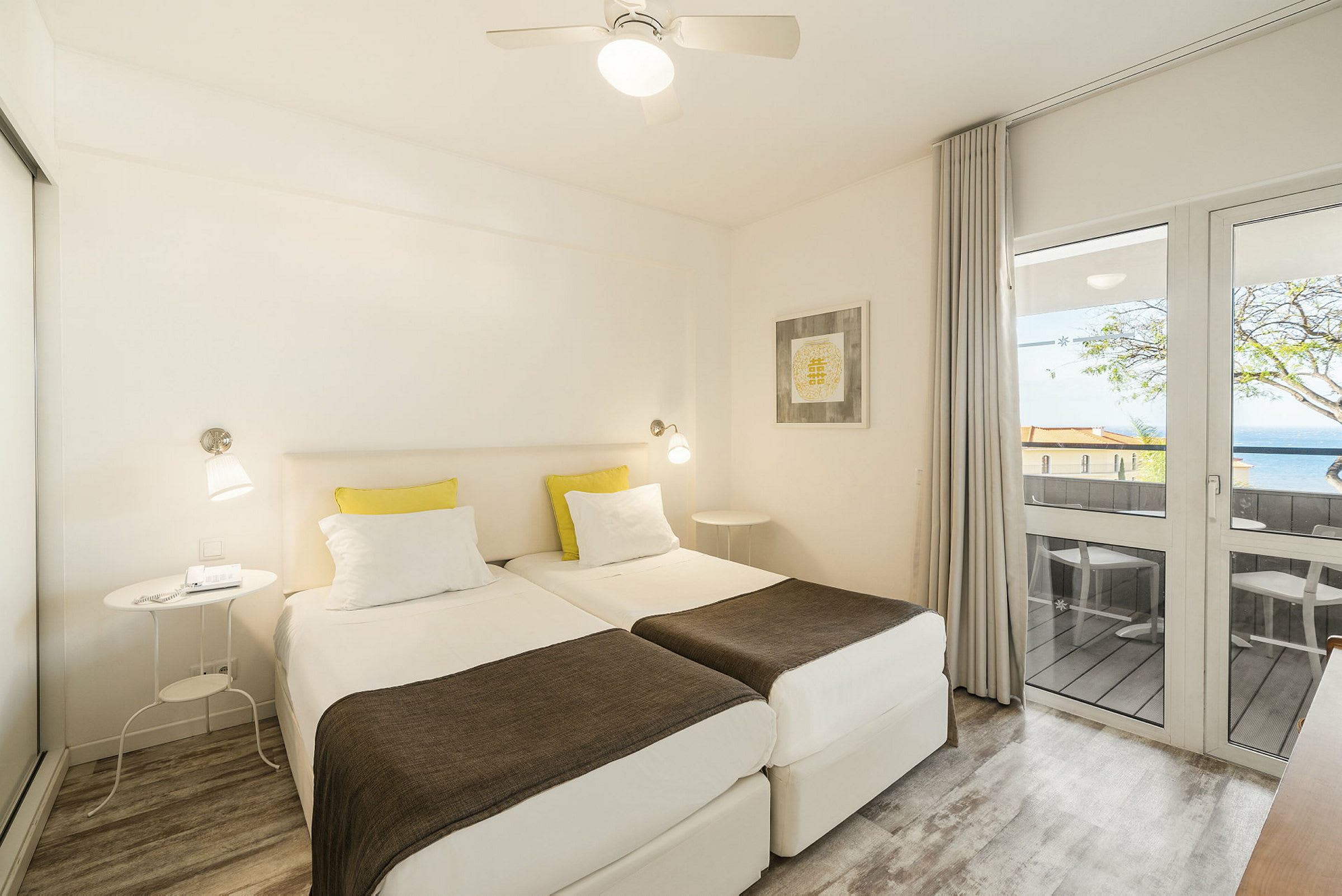 Hotellihuone, jossa on kaksi yhden hengen vuodetta, parveke ja vaaleat huonekalut. (Tekoälyn luoma teksti)