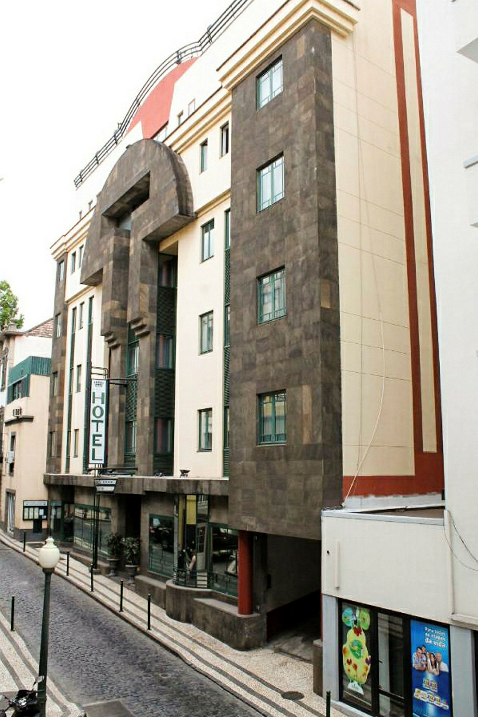 Hotellin julkisivu kaupunkimiljöössä, jossa on neonkyltti ja yksityiskohtainen arkkitehtuuri. (Tekoälyn luoma teksti)