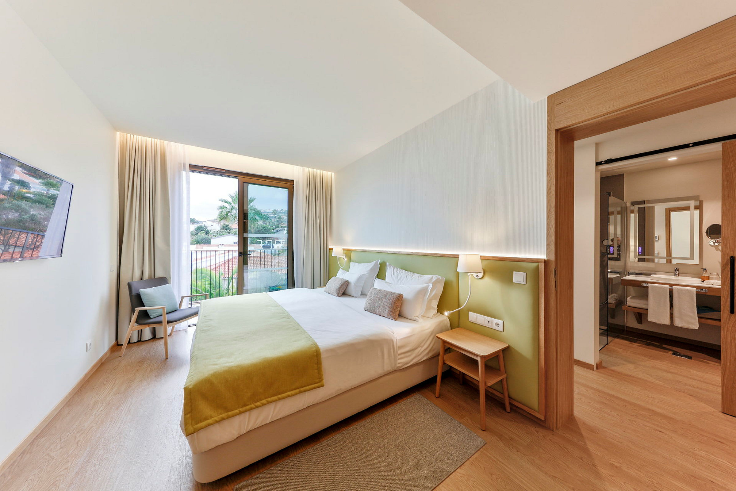 Hotellihuone, jossa on parivuode, nojatuoli ja avoin kylpyhuone. (Tekoälyn luoma teksti)