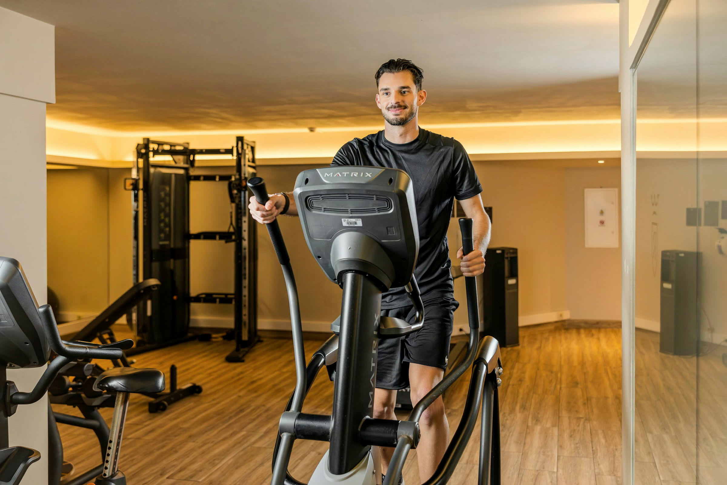 Henkilö harjoittelee cross trainerissa kuntosalilla. (Tekoälyn luoma teksti)
