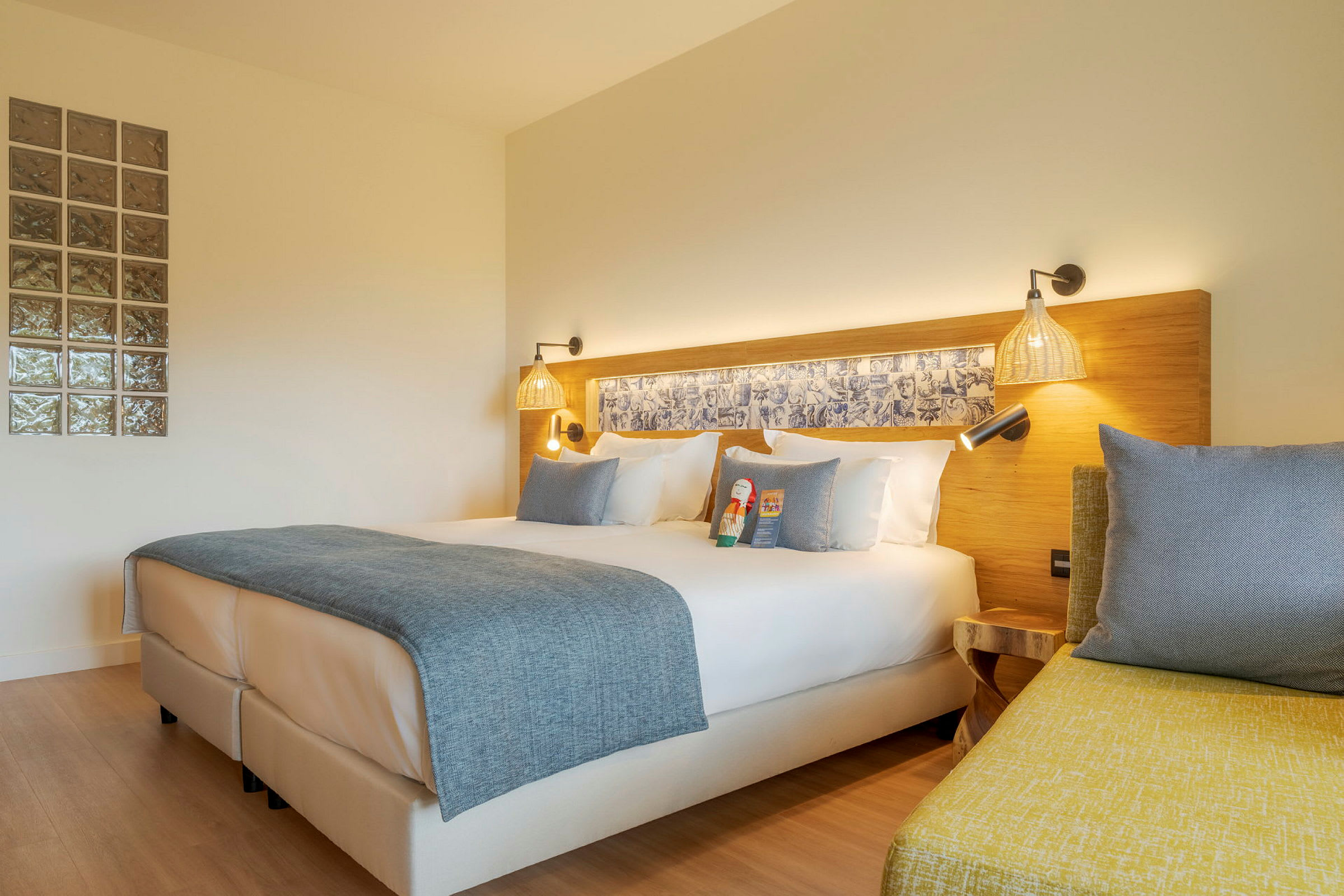 Moderni hotellihuone, jossa parivuode, valkoiset vuodevaatteet ja sininen päiväpeite. (Tekoälyn luoma teksti)
