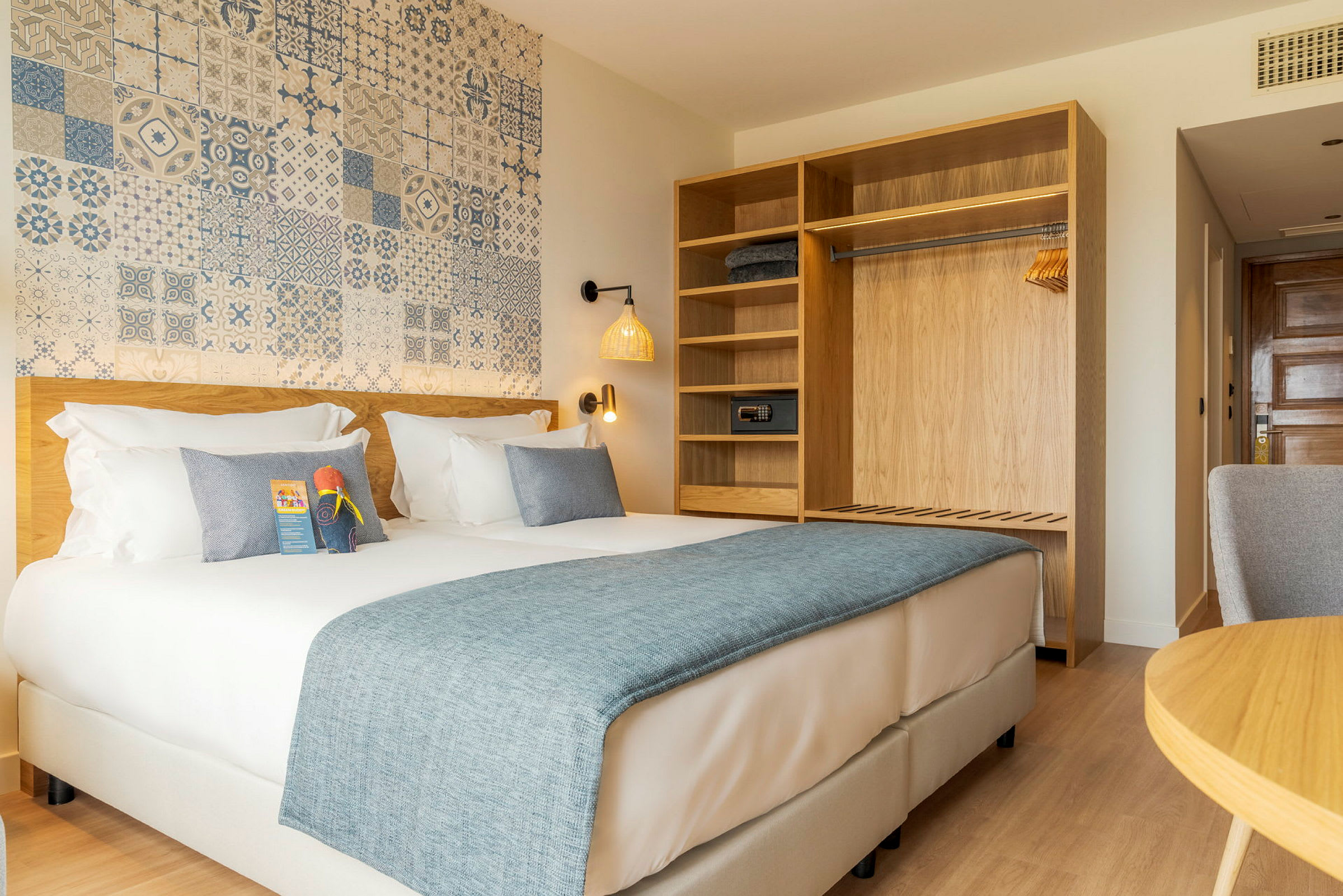 Hotellihuone, jossa on parivuode, kaappi hyllyillä ja koristeltu seinä. (Tekoälyn luoma teksti)