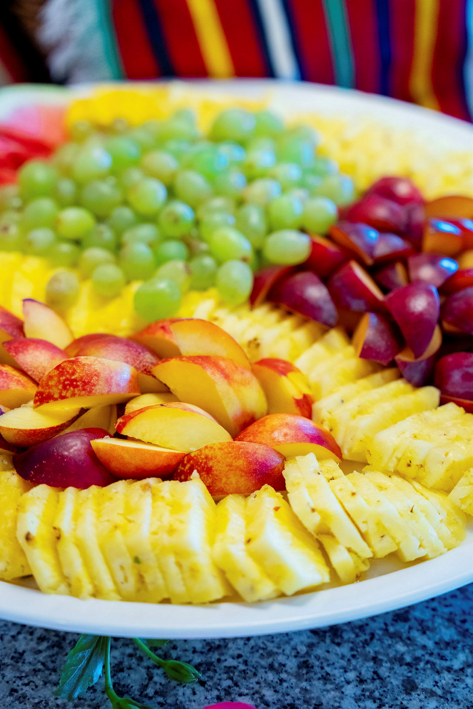 Lautasella viipaloitu ananas, viinirypäleitä, nektariineja ja punaisia hedelmiä. (Tekoälyn luoma teksti)