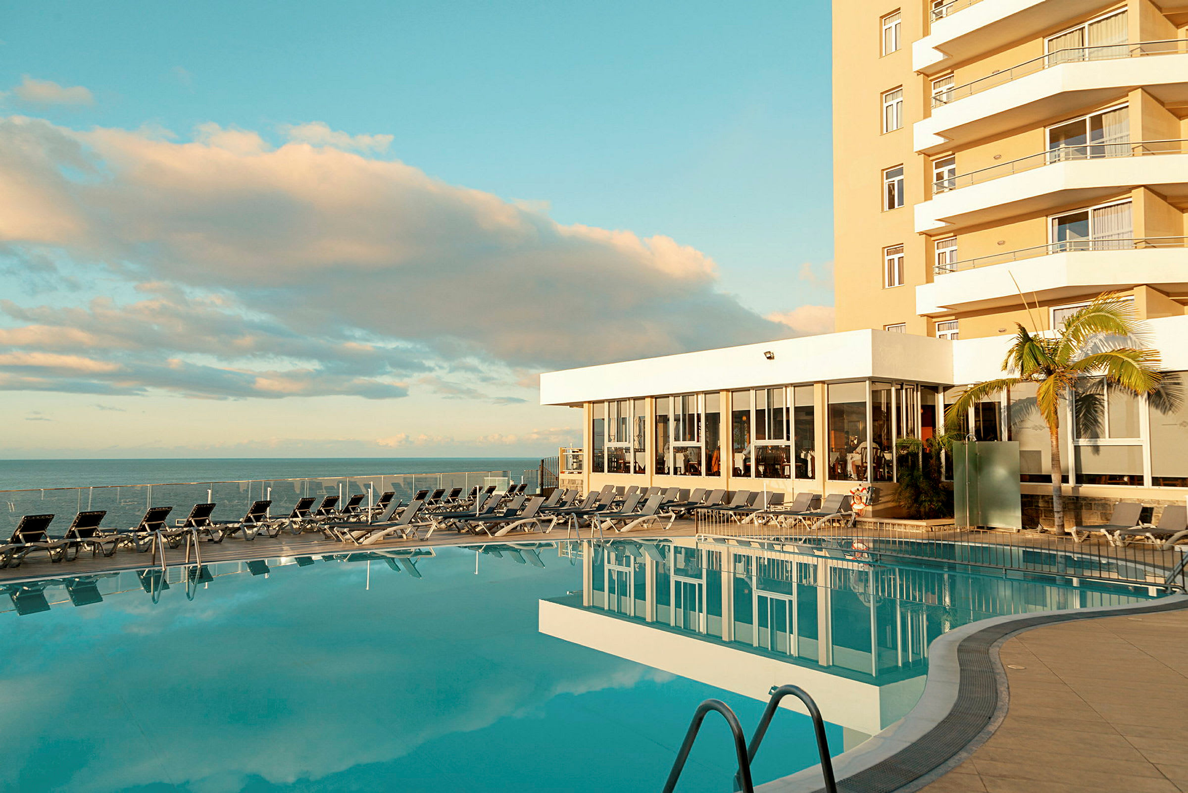 Ulkouima-allas hotellilla, aurinkotuoleja ja näkymä merelle. (Tekoälyn luoma teksti)
