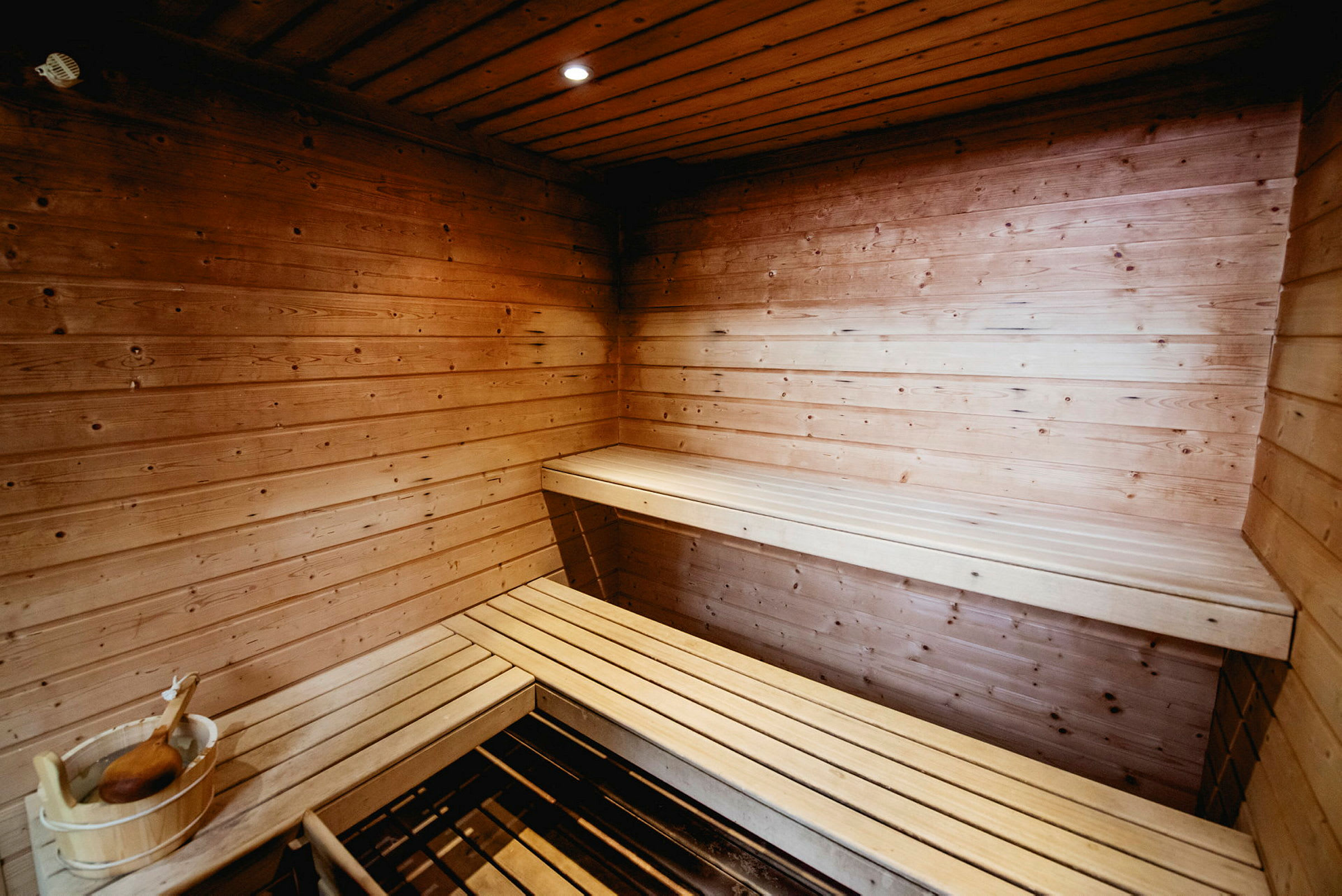Puuvuorattu sauna, jossa istumapenkit ja puinen kauhaämpäri. (Tekoälyn luoma teksti)