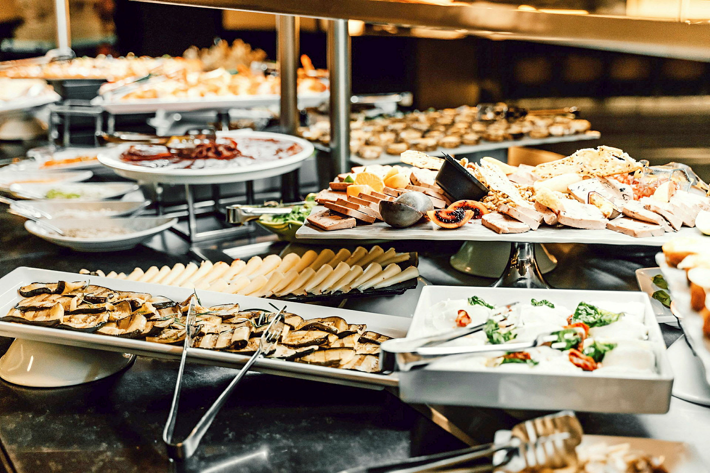 Kuva buffetista, jossa on juustoa, hedelmiä ja muita ruokatarvikkeita aseteltuna lautasille. (Tekoälyn luoma teksti)