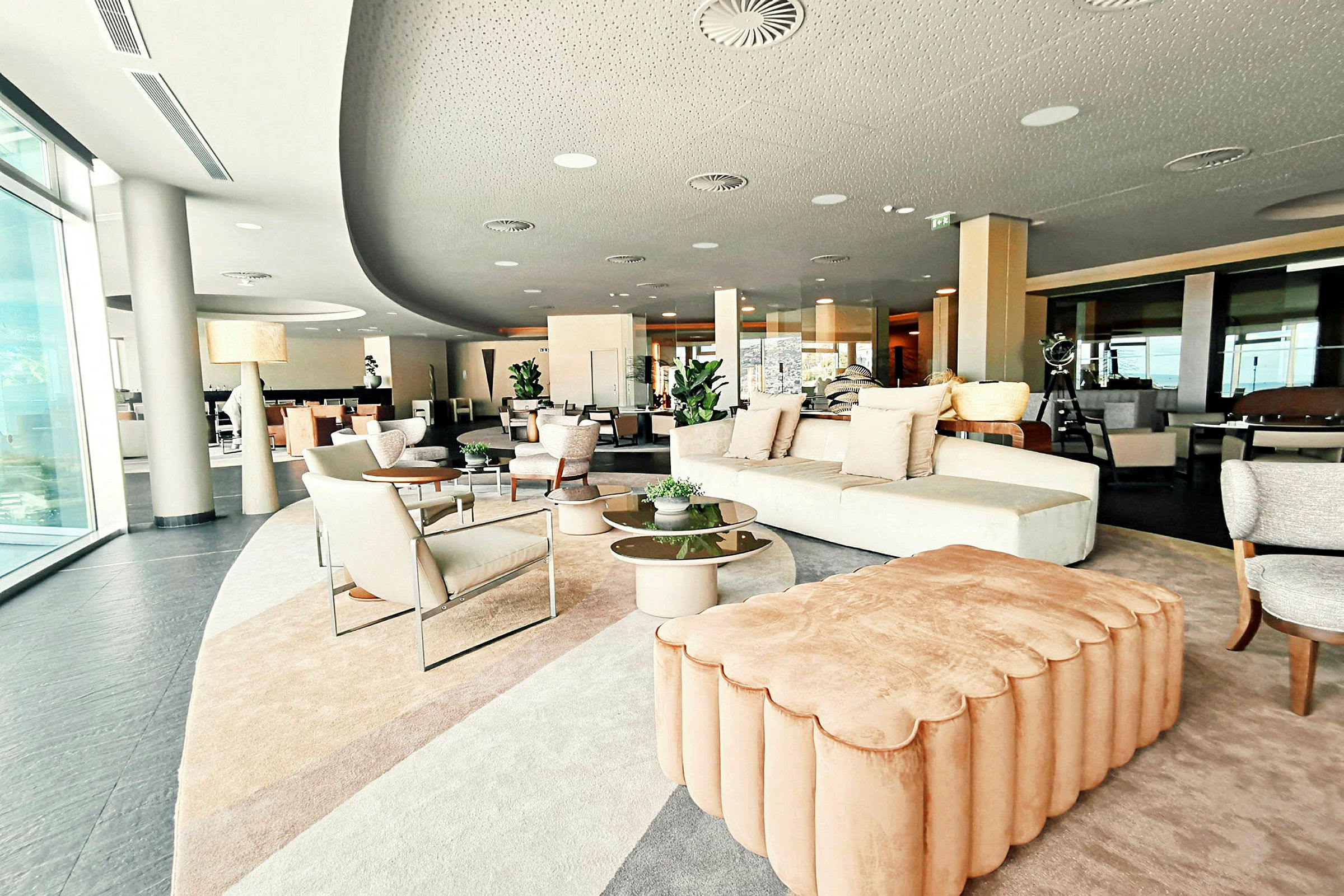 Modernisti sisustettu oleskelutila, jossa sohvia, nojatuoleja ja pöytiä kasveilla. (Tekoälyn luoma teksti)